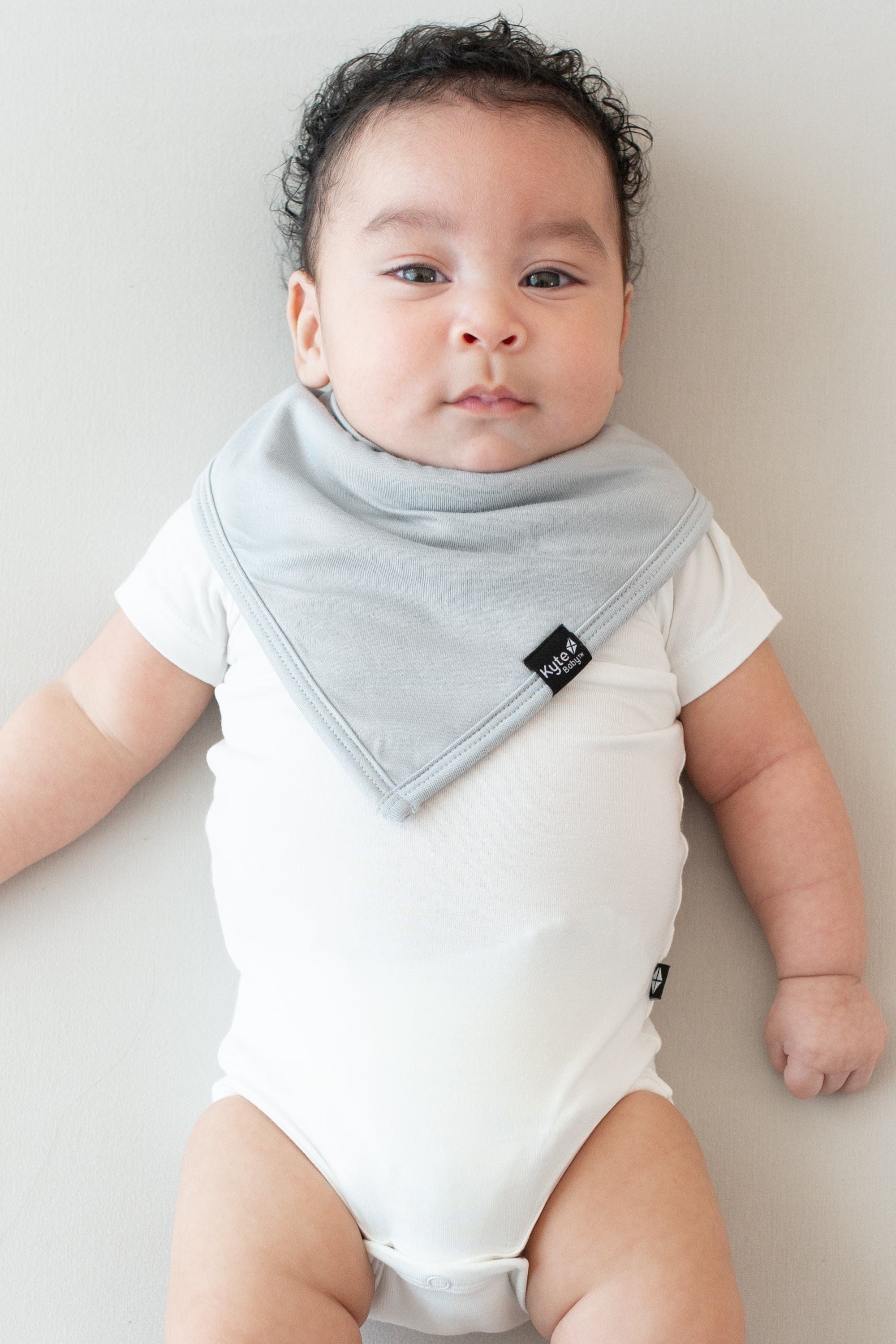 Infant wearing a Kyte Baby Bib in Storm and Short Sleeve Bodysuit in Cloud