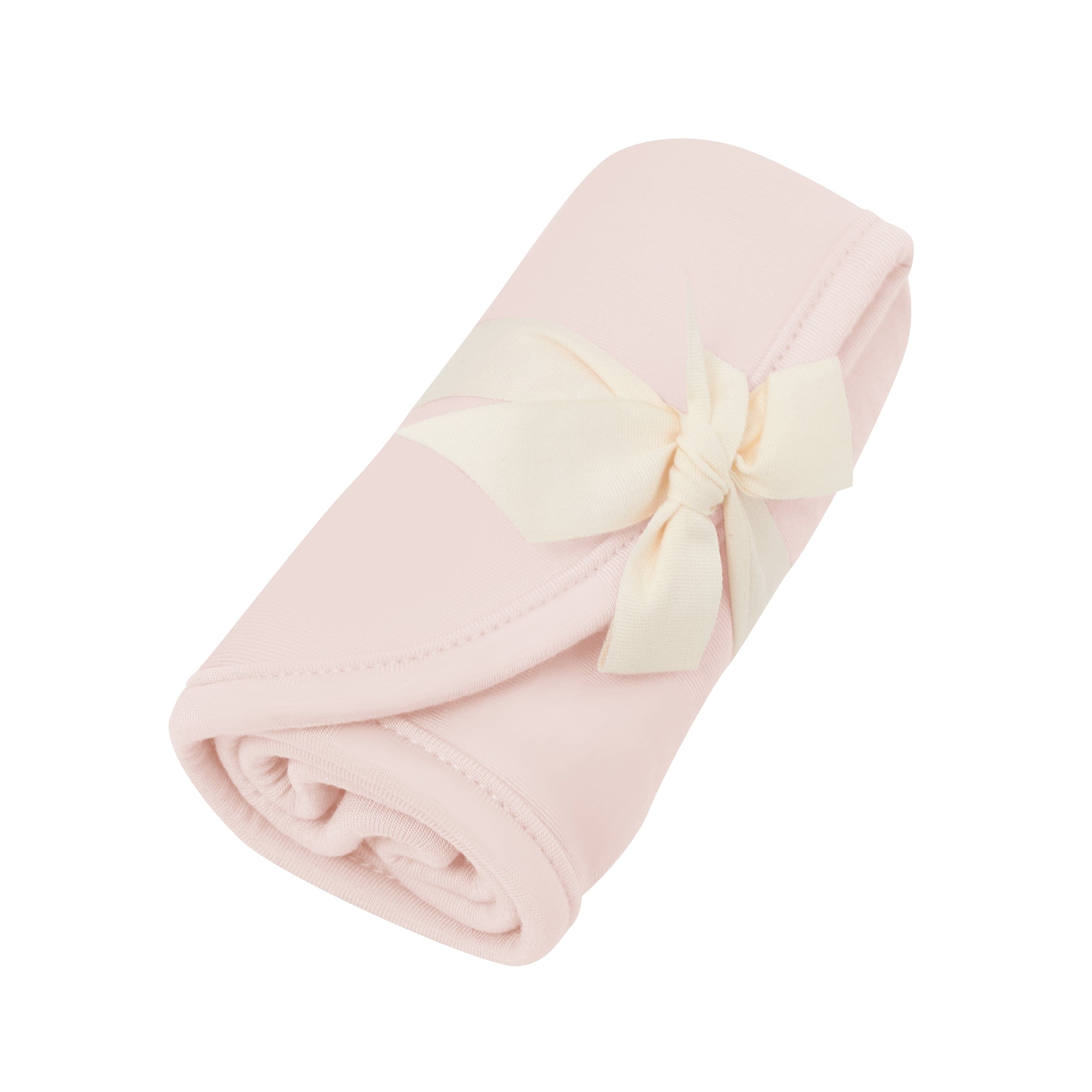 Rolled up Kyte Baby Burp Cloth in Blush tied with a bow