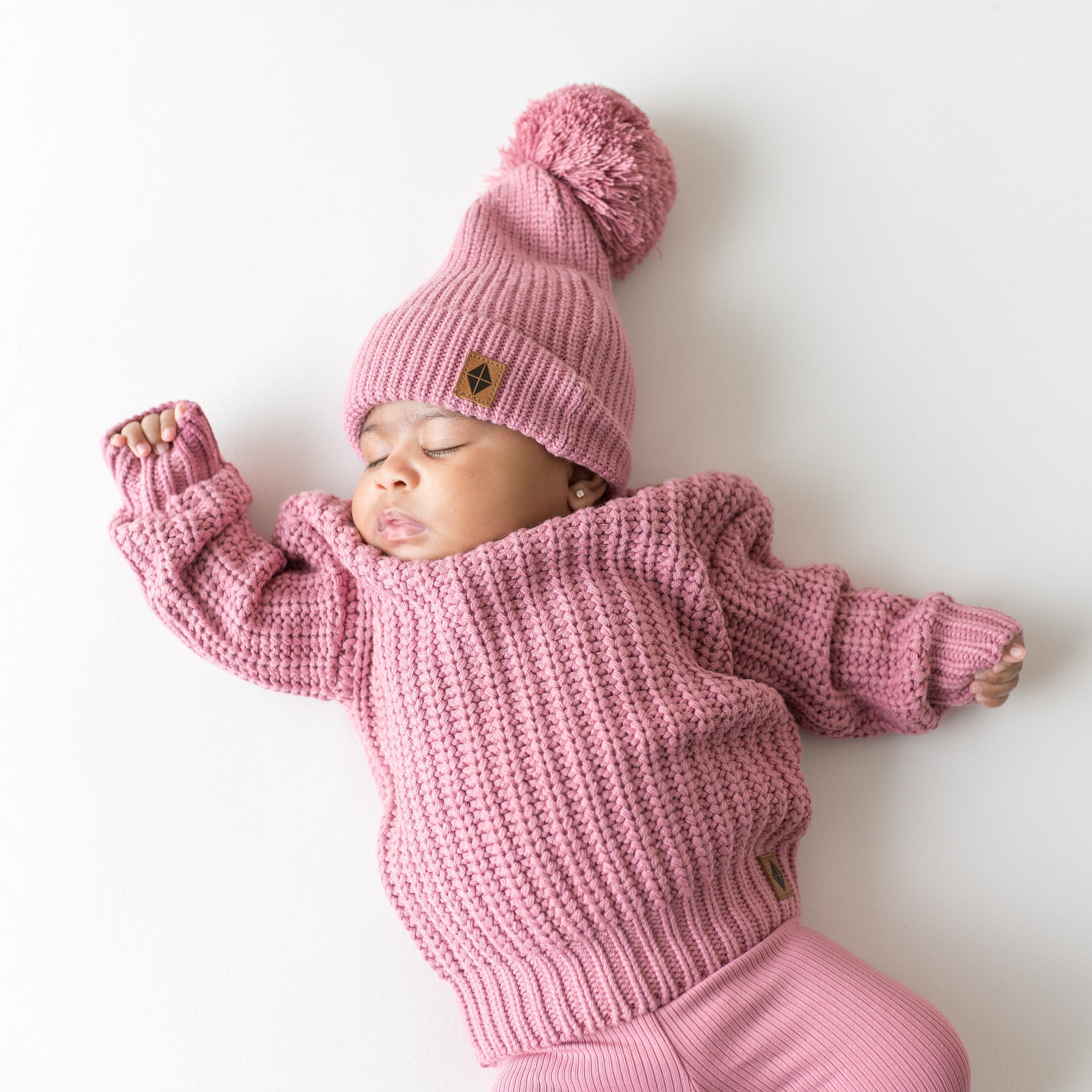 Infant wearing Kyte Baby Chunky Knit Pom Beanie in Apple Blossom