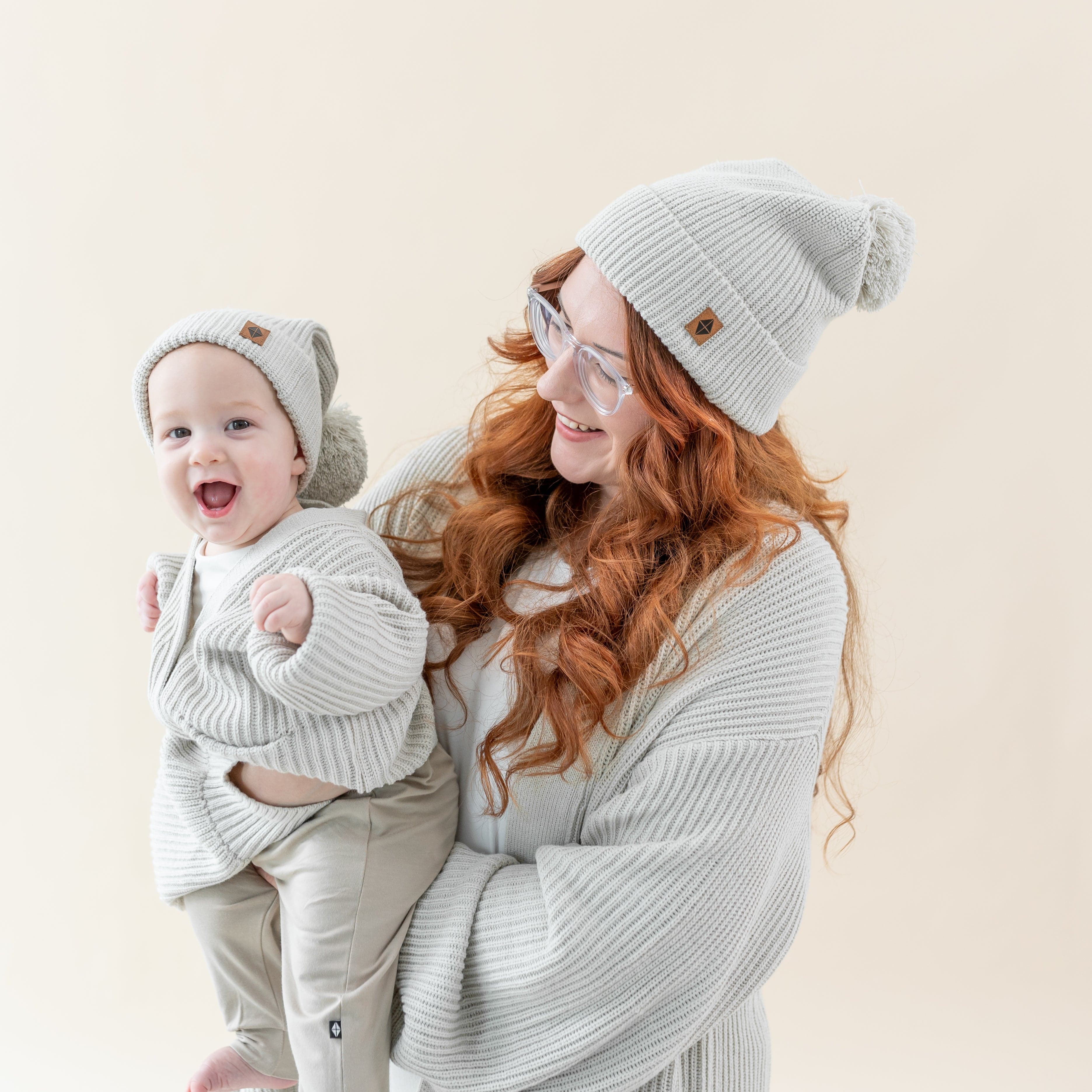 Mom and child wearing matching Kyte Baby Chunky Knit Pom Beanies and Cardigans inOat