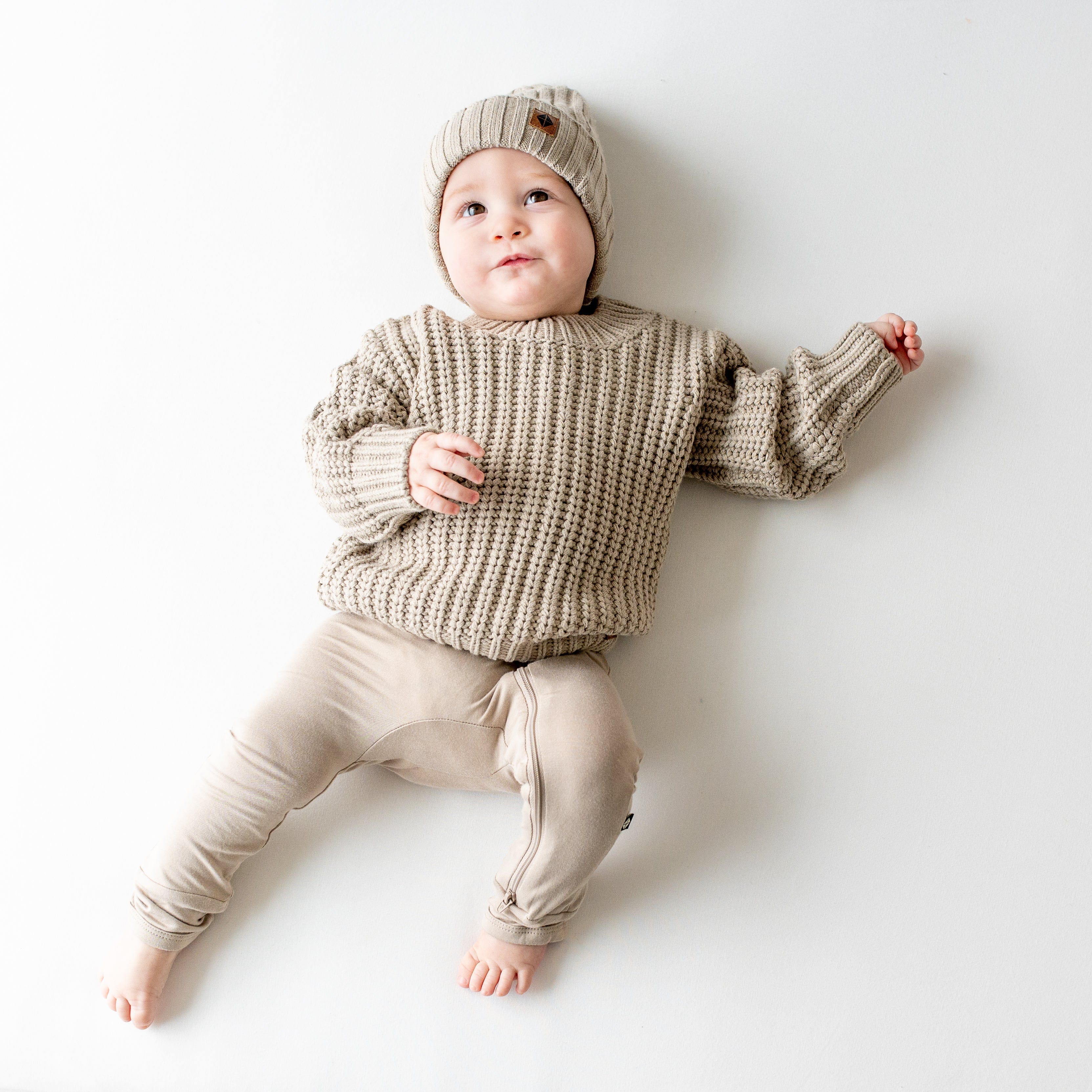 Infant wearing soft and stretchy Kyte Baby Chunky Knit Sweater in Almond