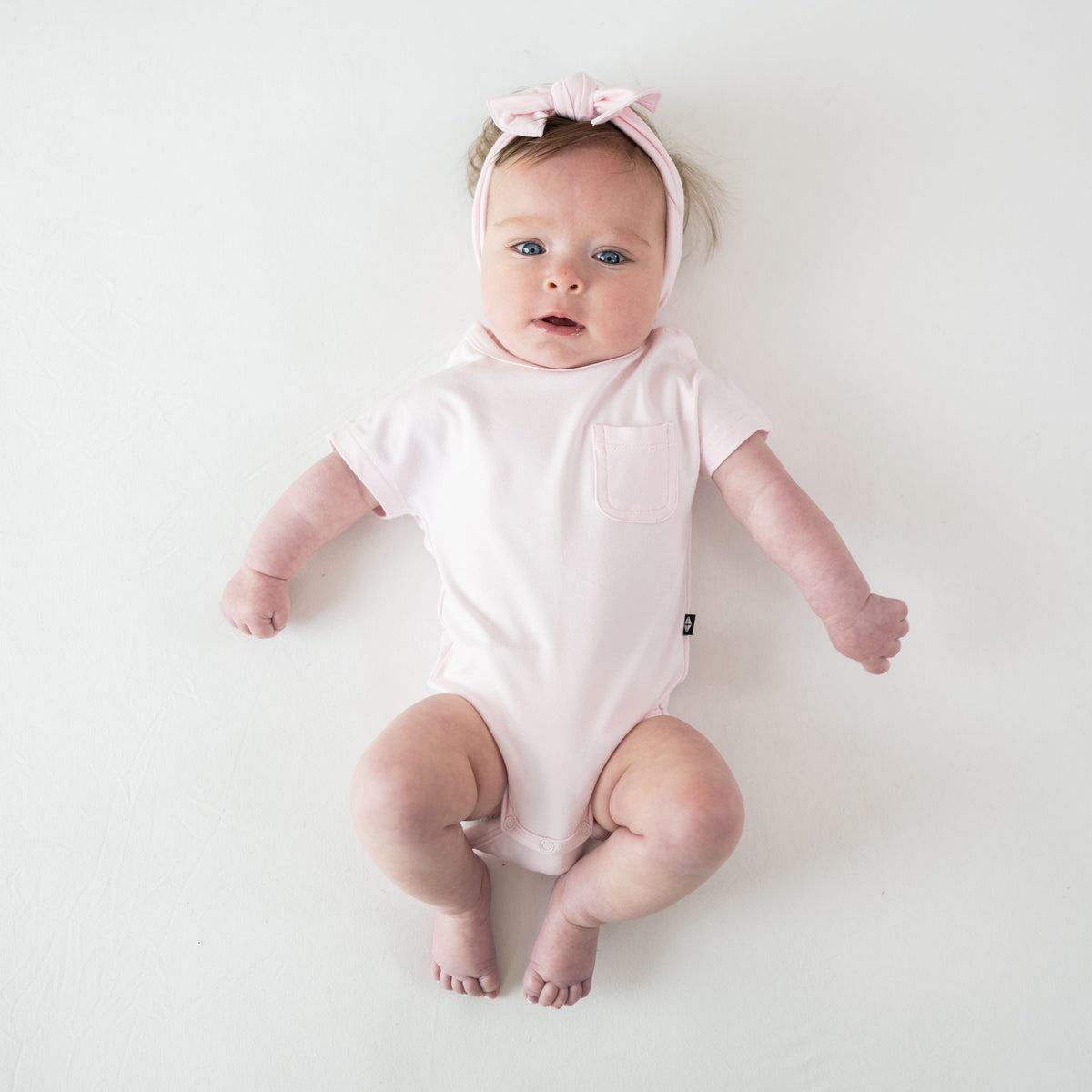 Infant wearing Kyte Baby Crew Neck Tee Bodysuit in Sakura