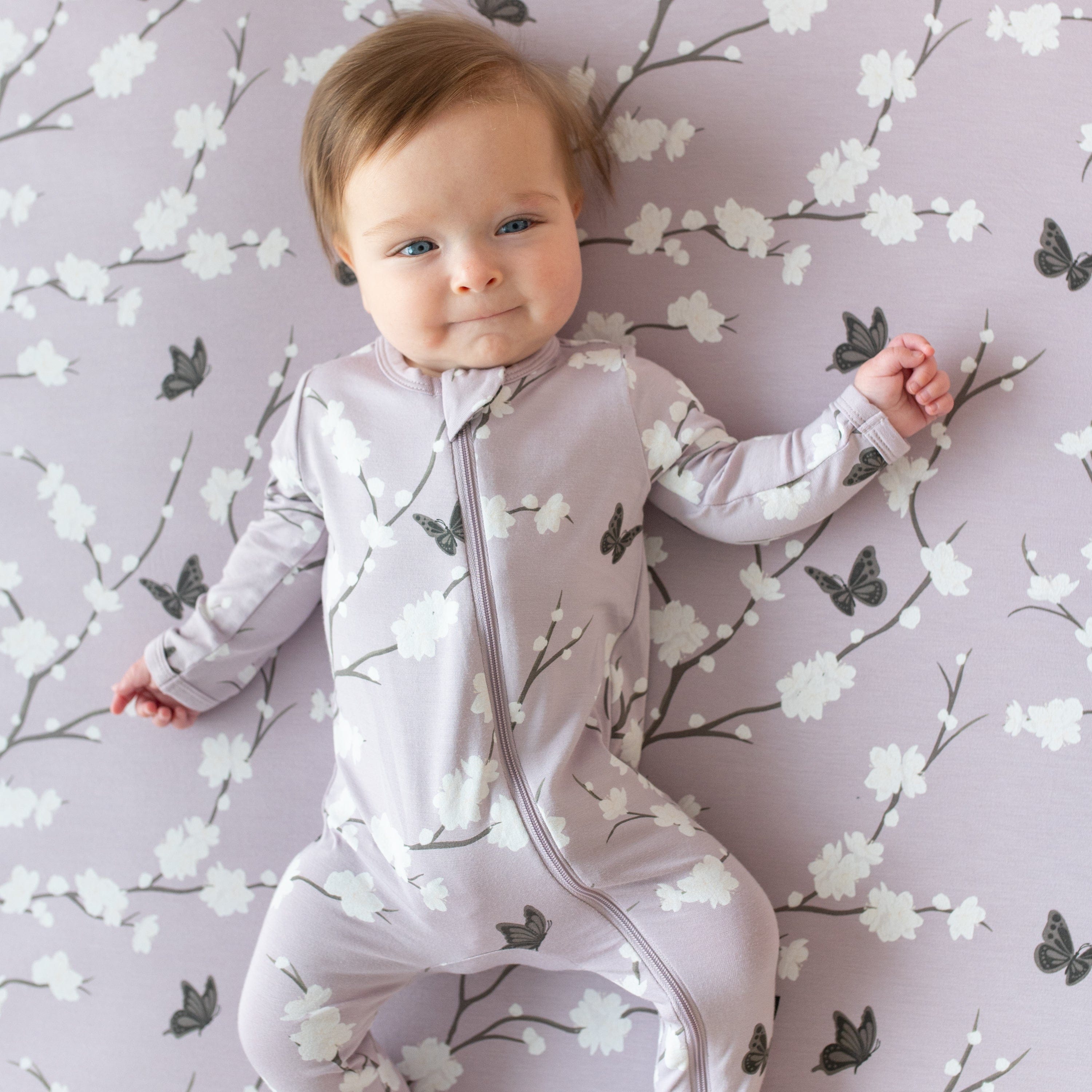 Infant laying on Kyte Baby Crib Sheet in Cherry Blossom