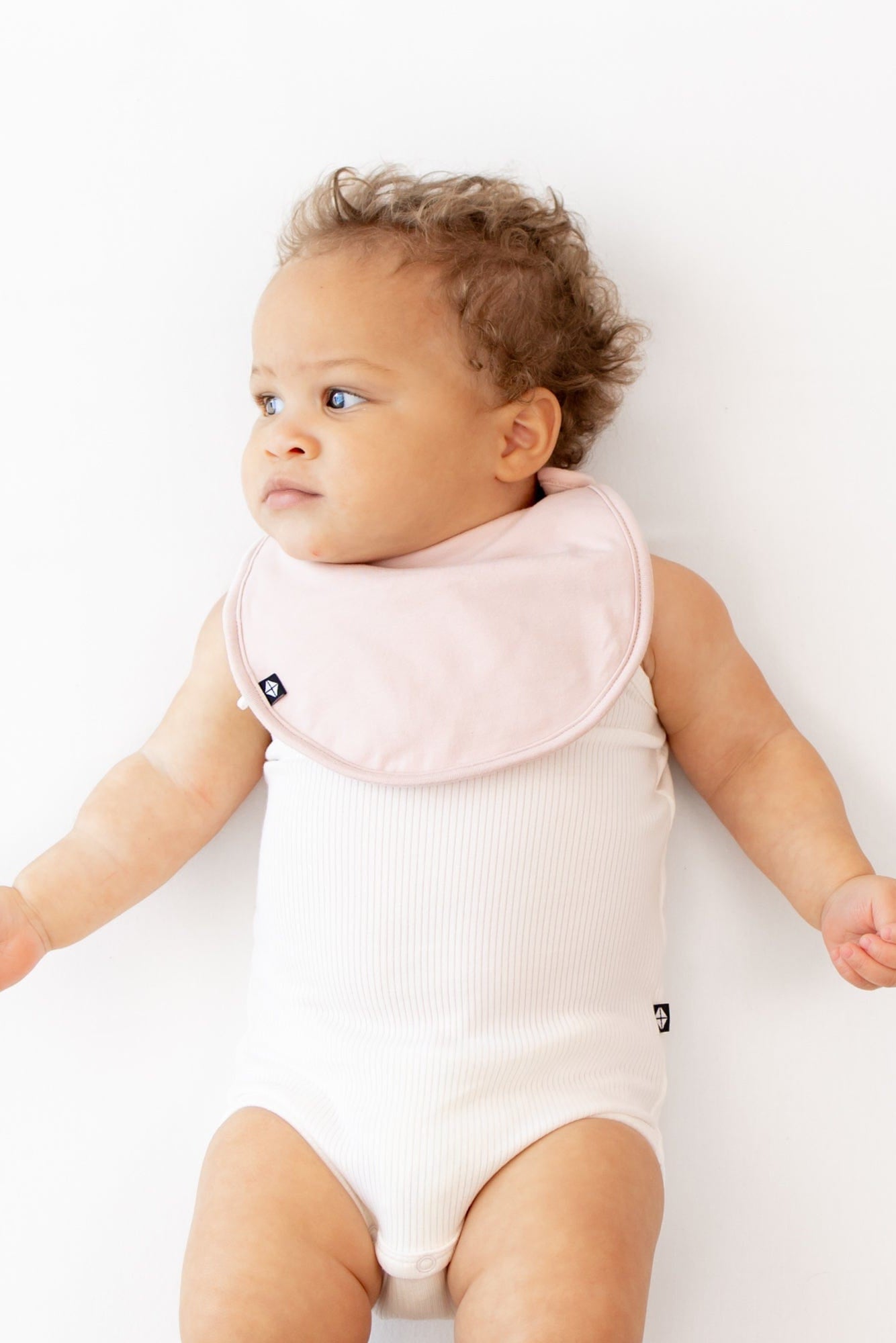 Infant wearing Kyte Baby Bamboo Cushy Bib in Blush pink