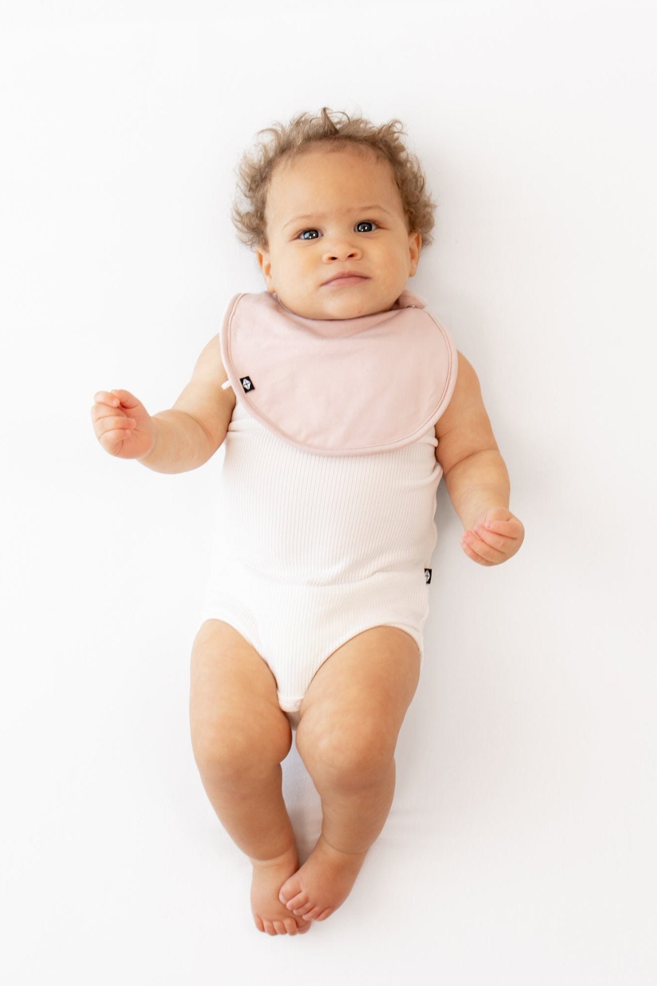Infant wearing Kyte Baby Cushy Bib with adjustable snaps in Blush