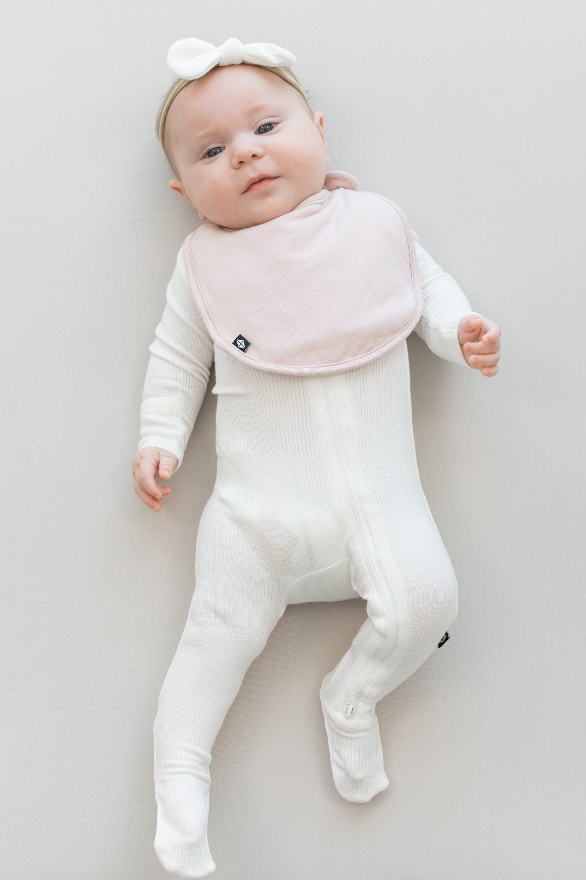 Infant wearing Kyte Baby Cushy Bib in Blush