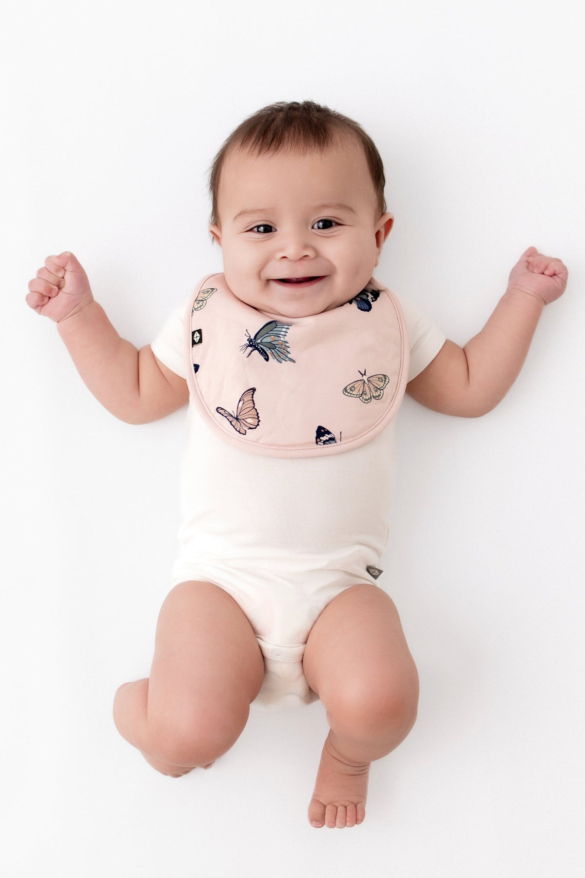 Infant wearing Kyte Baby Bamboo Cushy Bib in Blush Butterfly