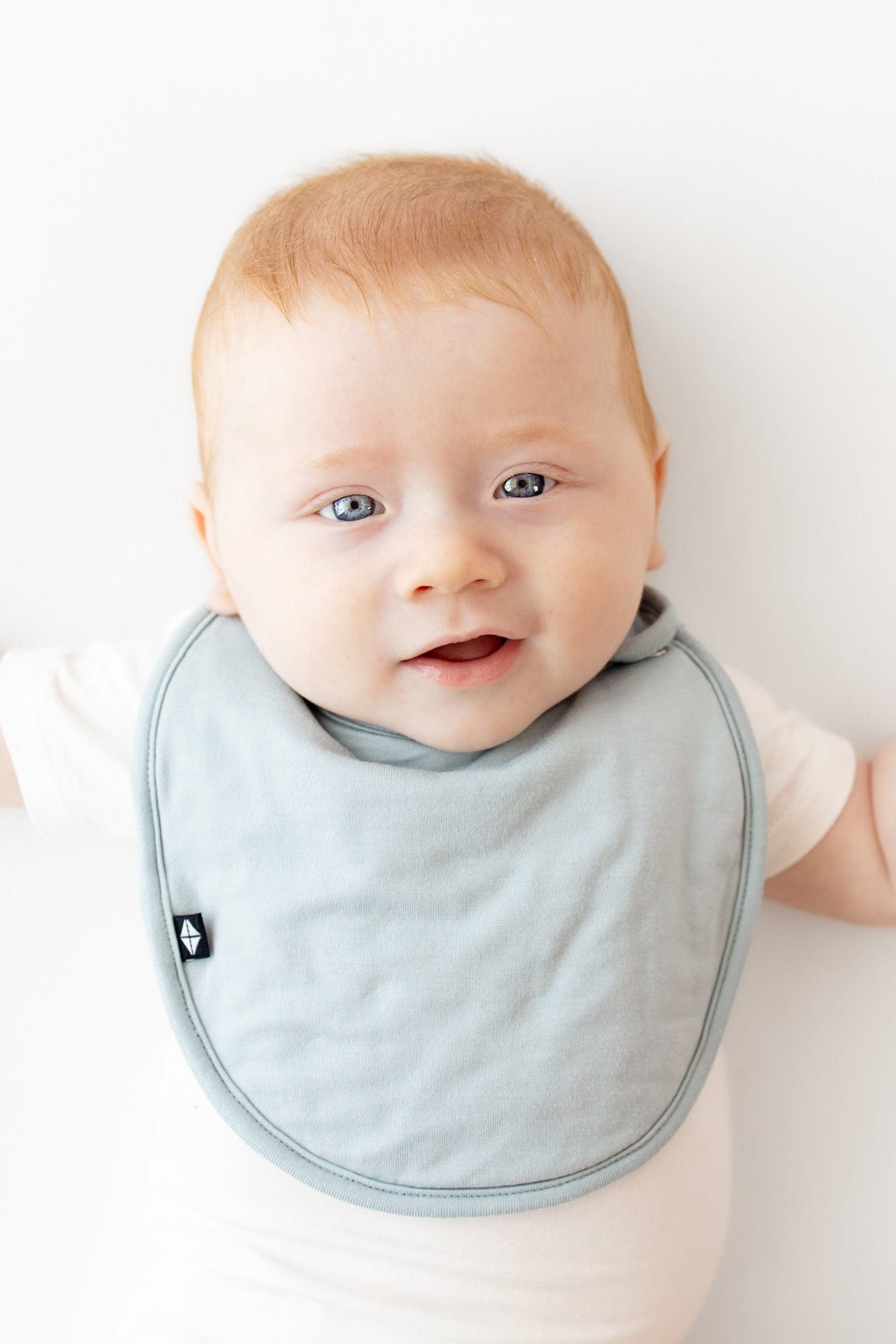 Infant wearing Kyte Baby Cushy Bib in Fog