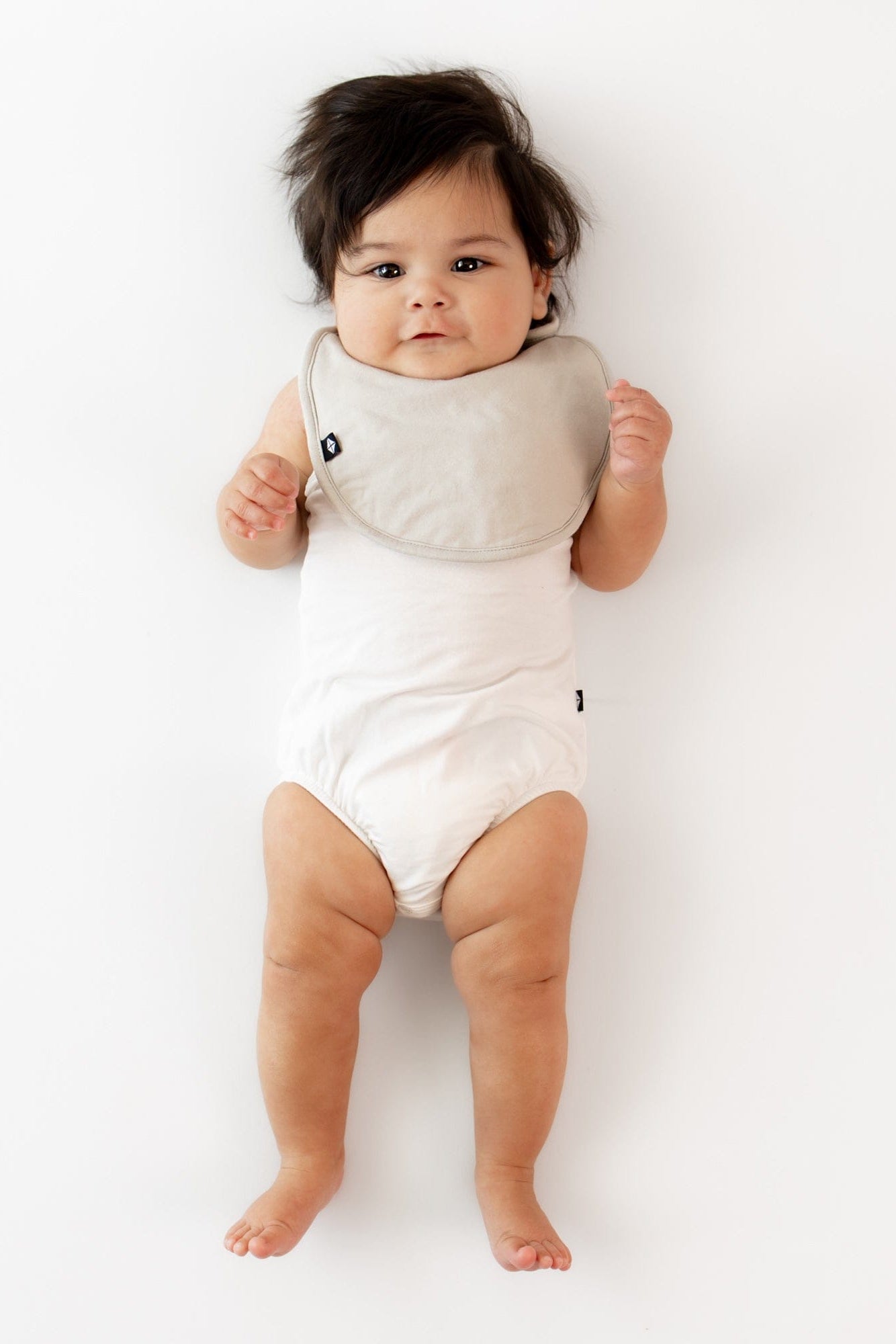 Infant wearing Kyte Baby Cushy Bamboo Bib in Oat