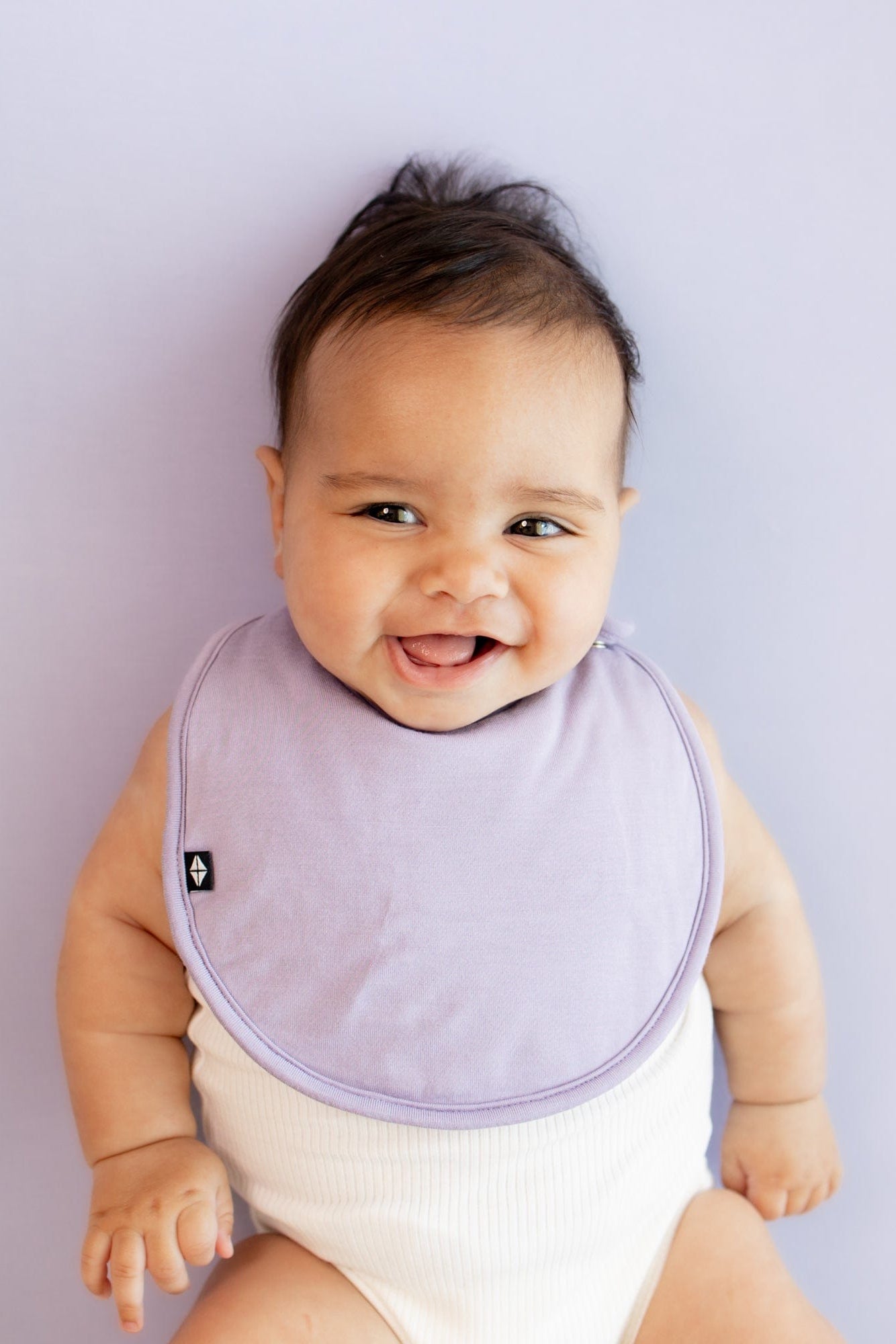 Infant wearing Kyte Baby Cushy Bamboo Bib in Taro
