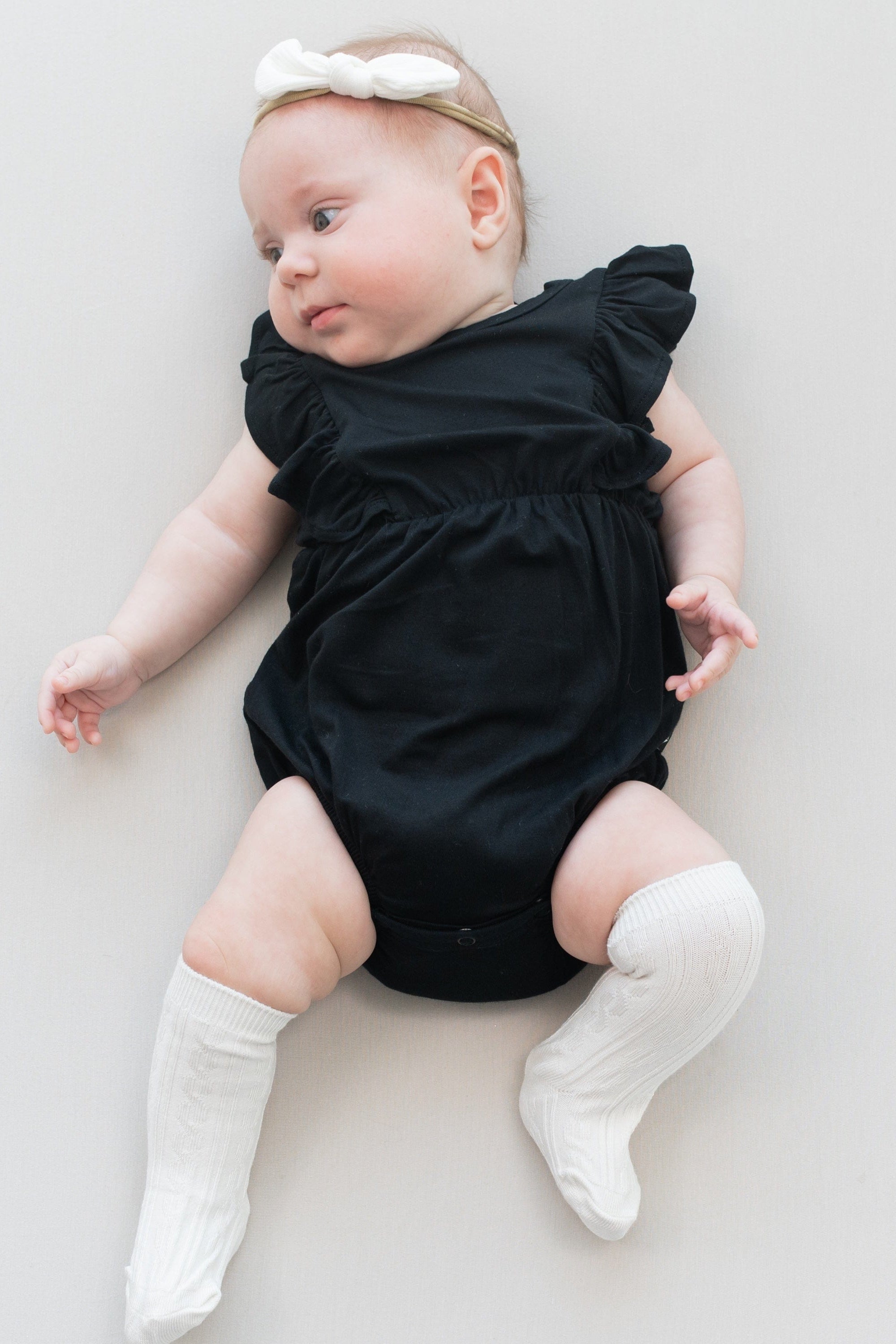 Infant wearing Kyte Baby Knee High Socks with ribbed cuff in Oat