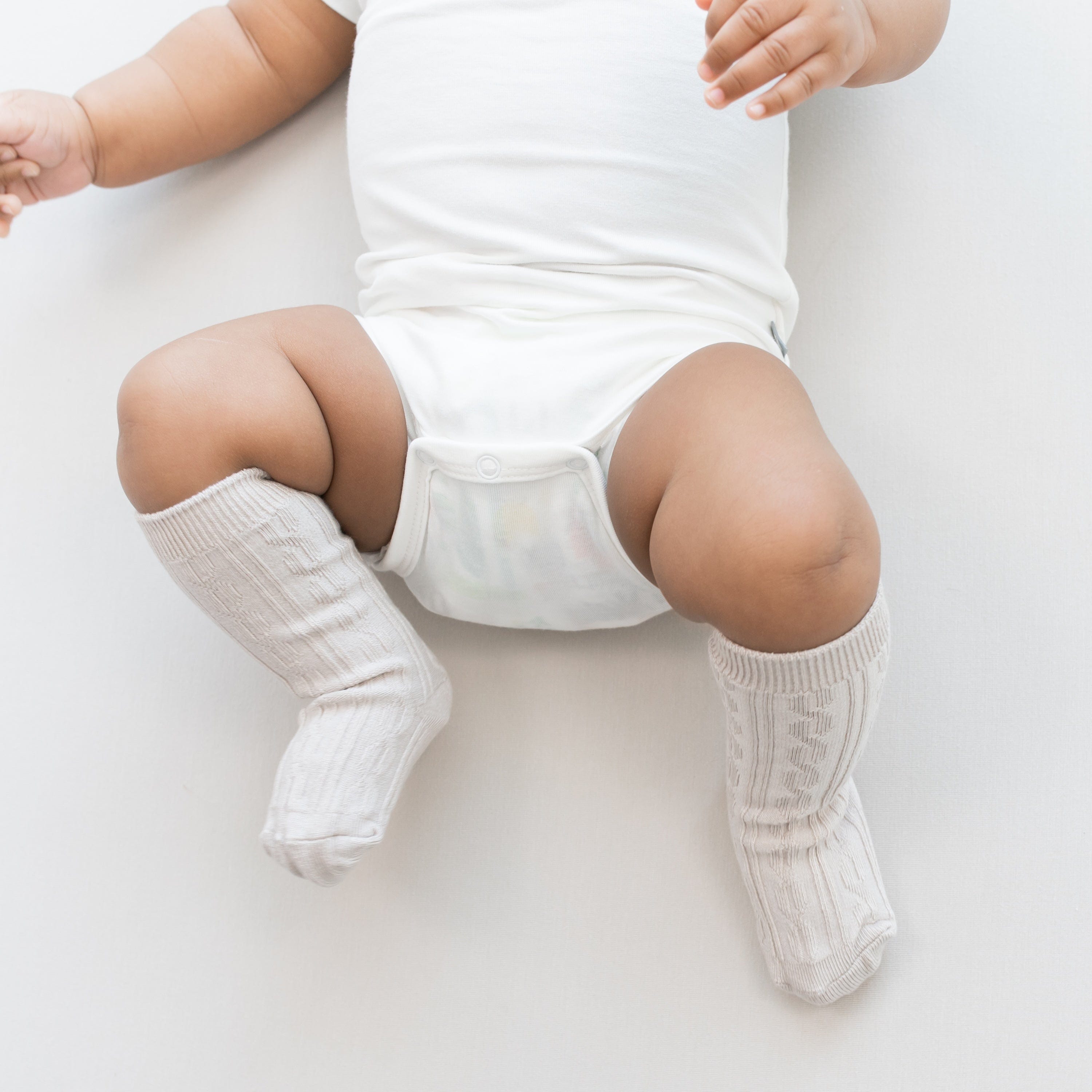 Infant wearing Kyte Baby cable knit Knee High Socks in Oat