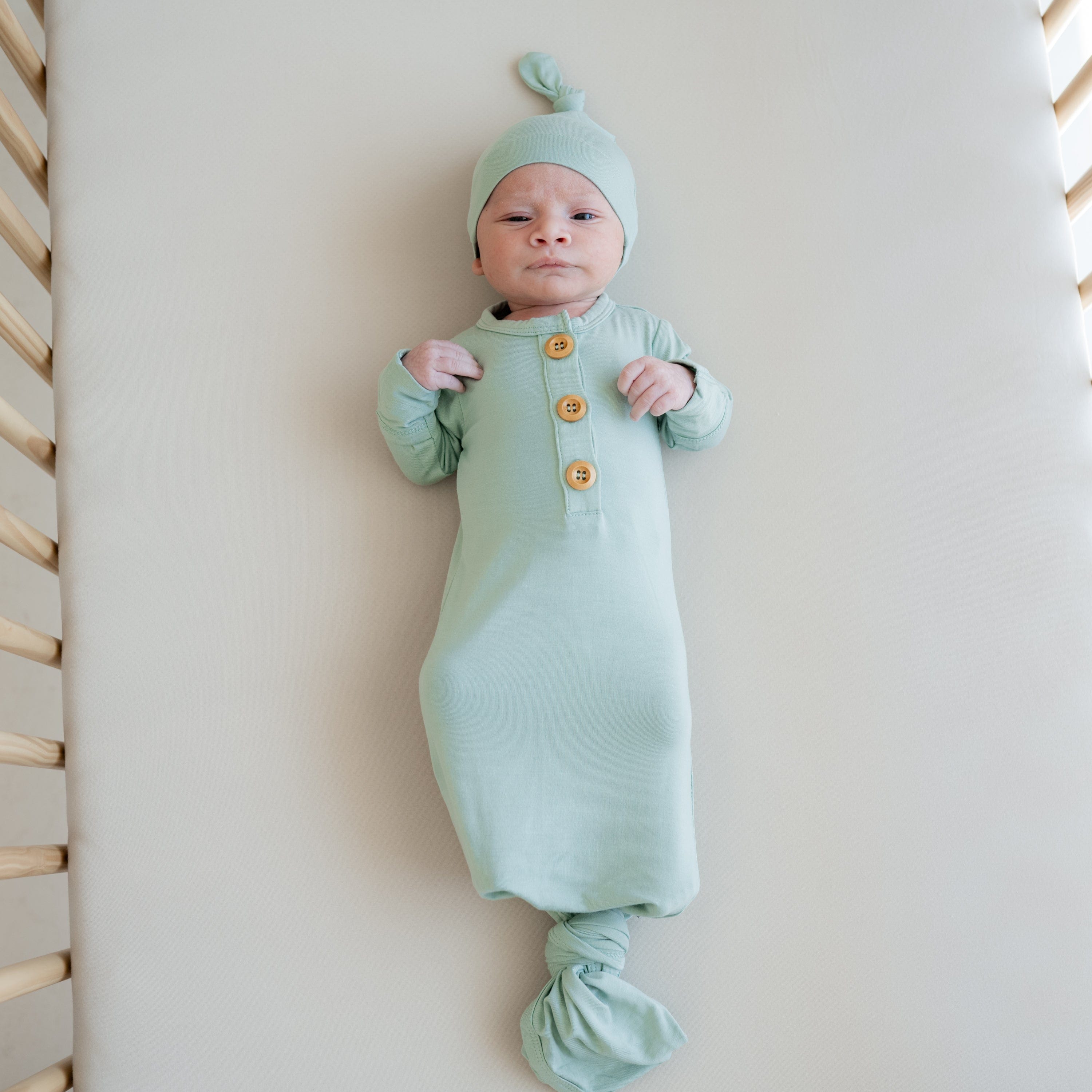 Baby wearing Kyte Baby Knotted Gown with Hat Set in Sage