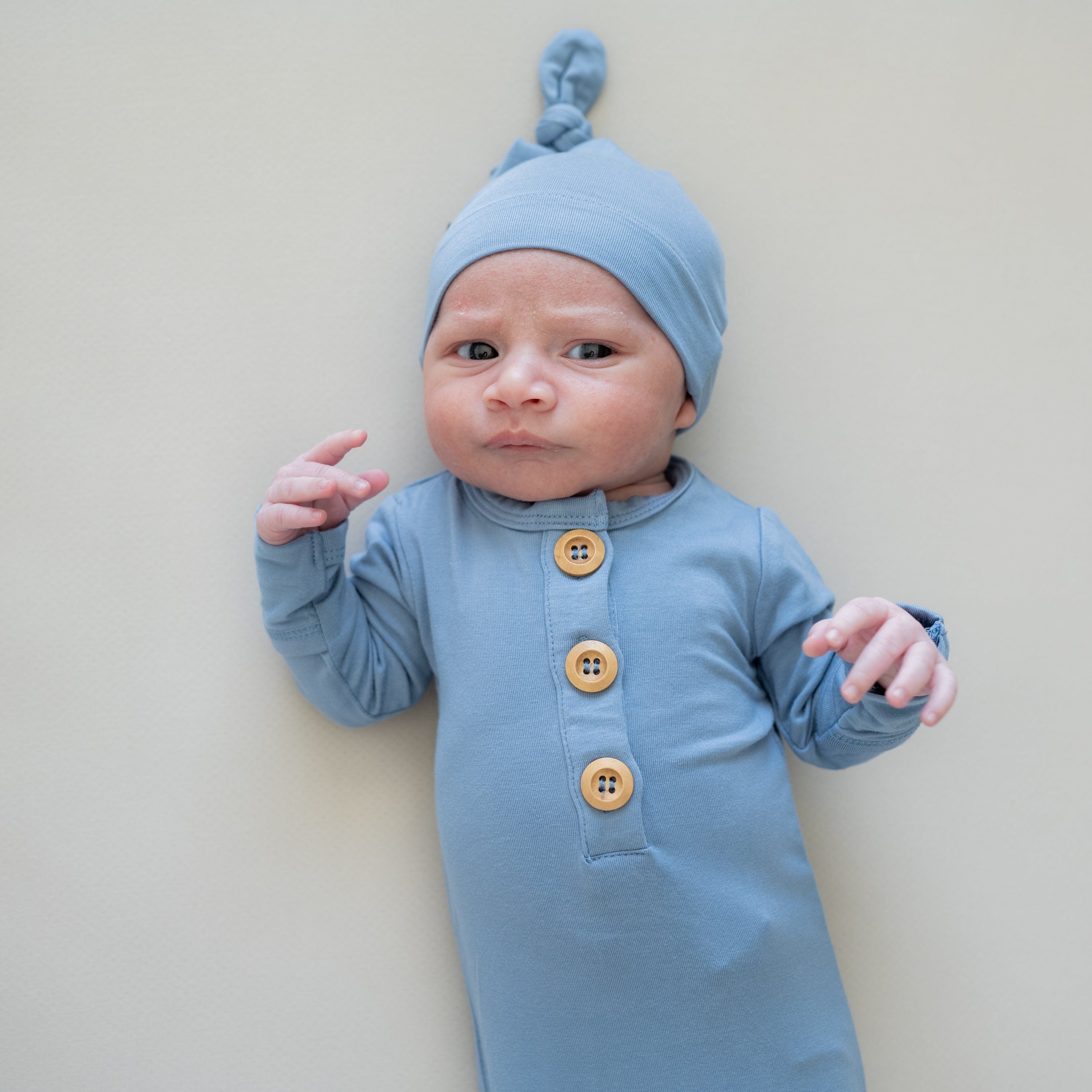 Newborn wearing Kyte Baby Knotted Gown with Hat Set in Slate with wooden buttons