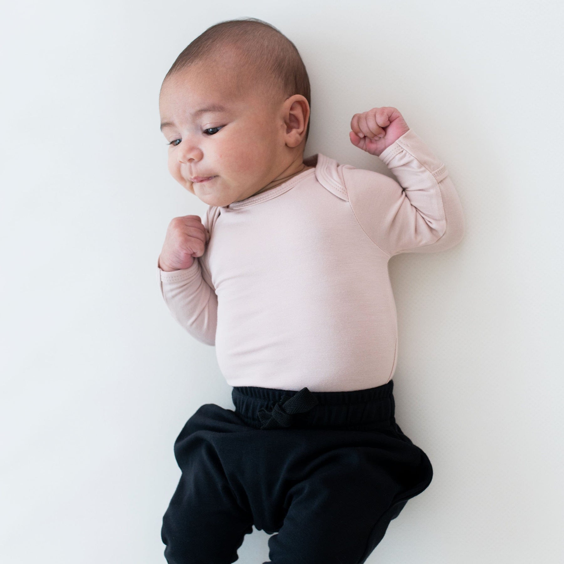 Newborn wearing Kyte Baby Long Sleeve Bodysuit in Blush