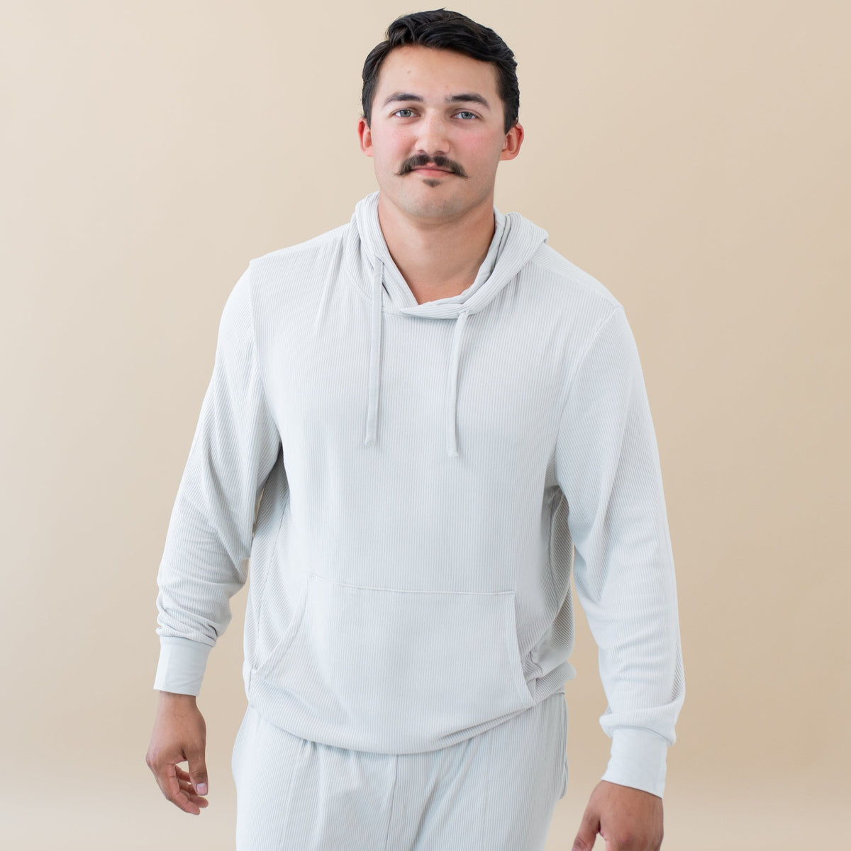 Man wearing Kyte Baby Men's Ribbed Hoodie in Oat