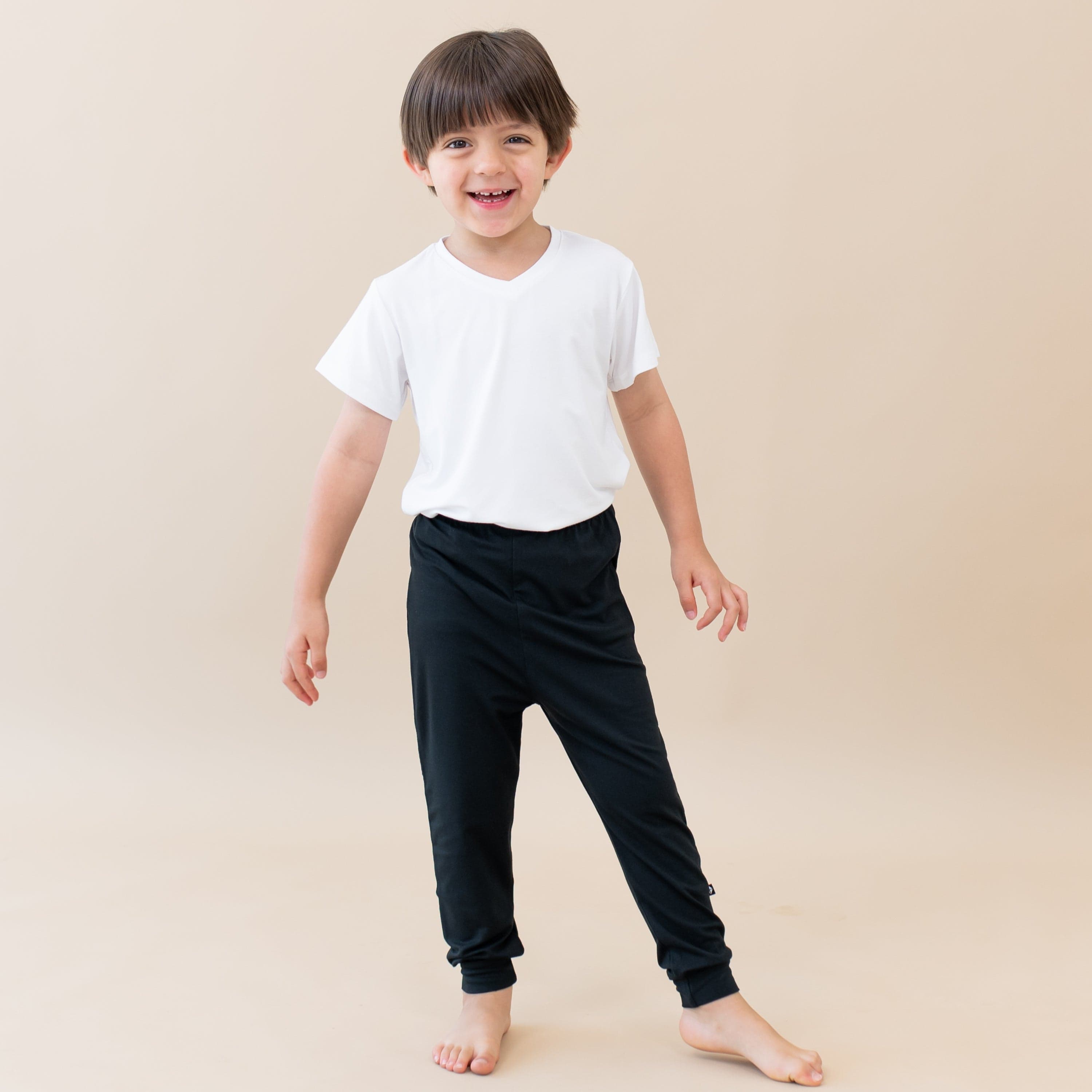 Smiling toddler standing while wearing Kyte Baby Pants in Midnight and V Neck in Cloud