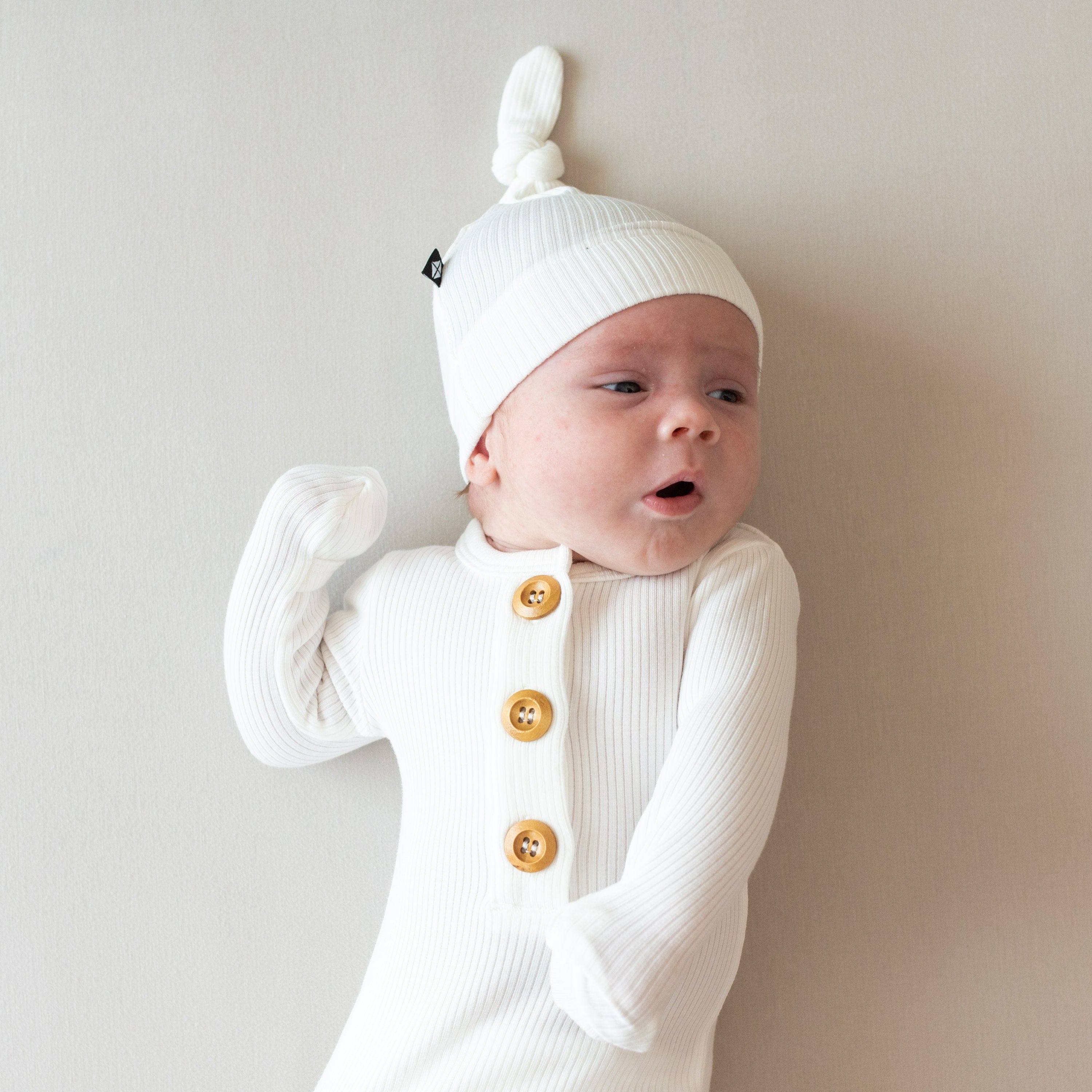 Baby wearing Kyte Baby Ribbed Knotted Gown with Hat Set in Cloud with wooden buttons