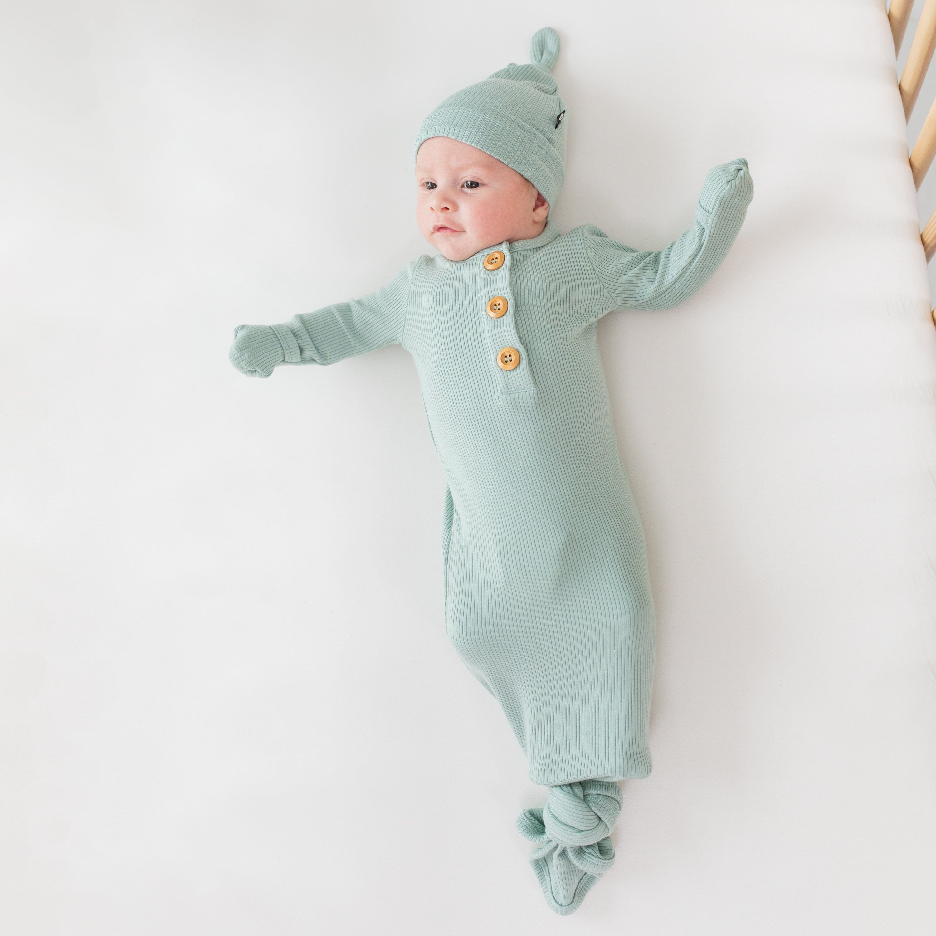 Baby wearing Kyte Baby Ribbed Knotted Gown with Hat Set in Sage