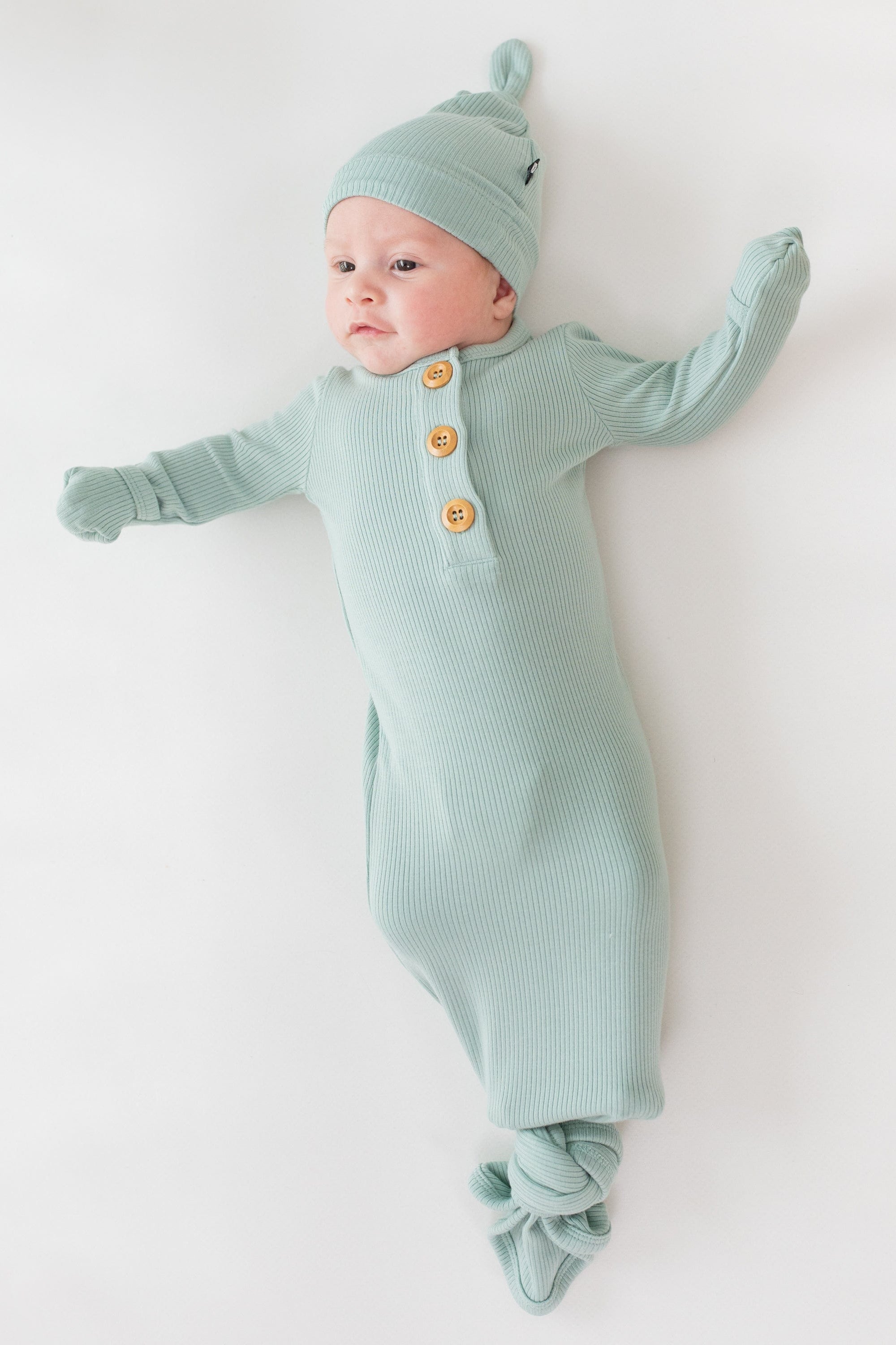 Baby wearing Kyte Baby Ribbed Knotted Gown with Hat Set in Sage