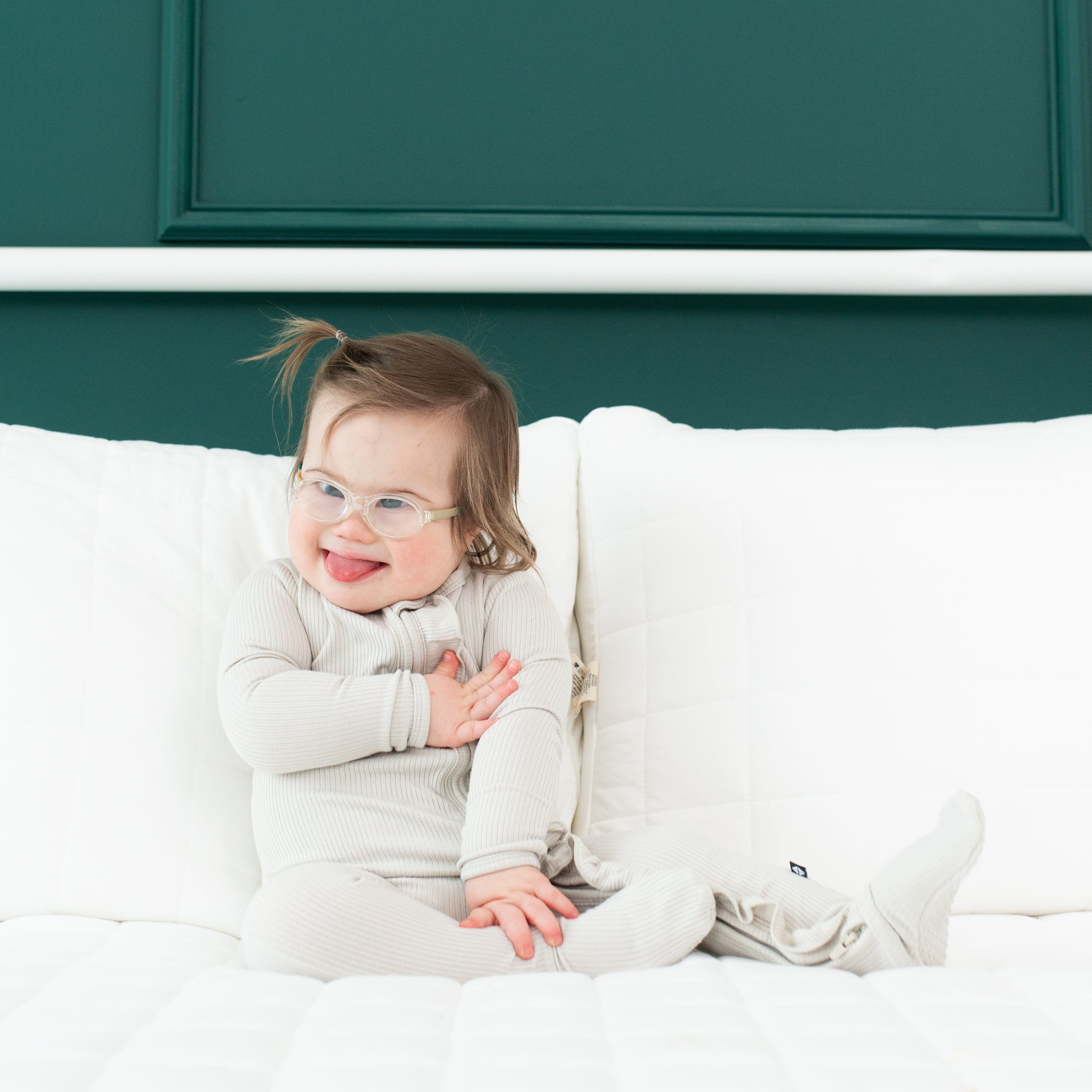 Toddler wearing Kyte Baby Ribbed Ruffle Zipper Footie in Oat