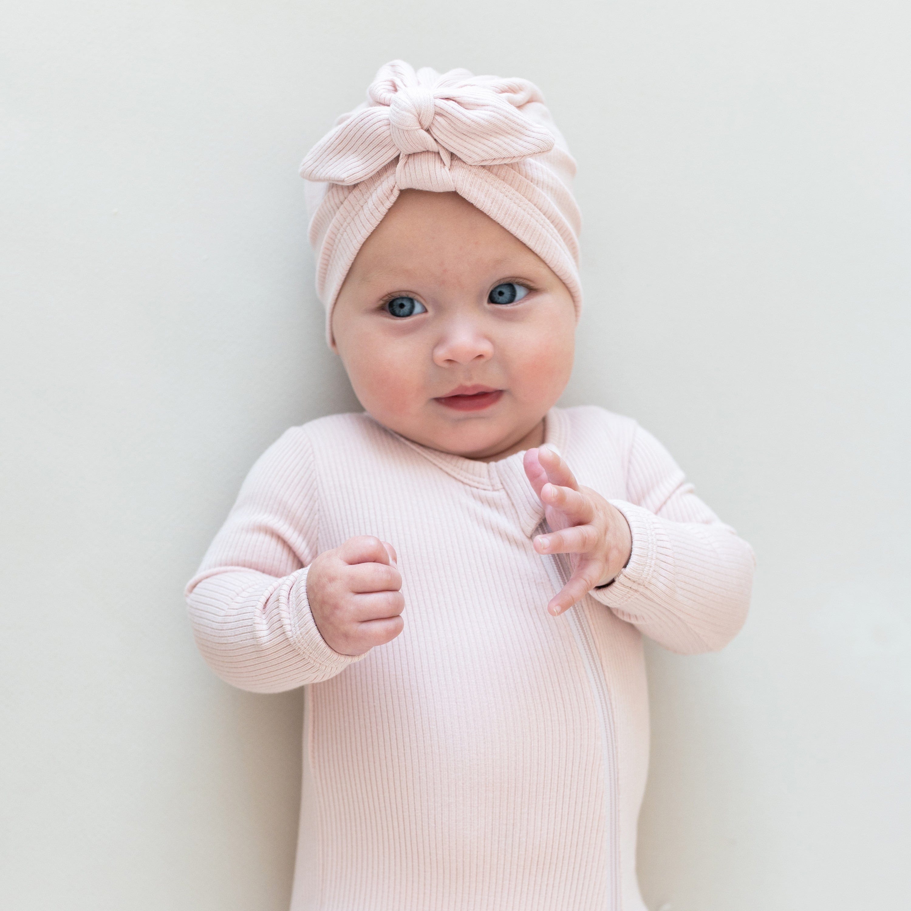 Baby wearing Kyte Baby bamboo Ribbed Zippered Footie pajamas in Blush