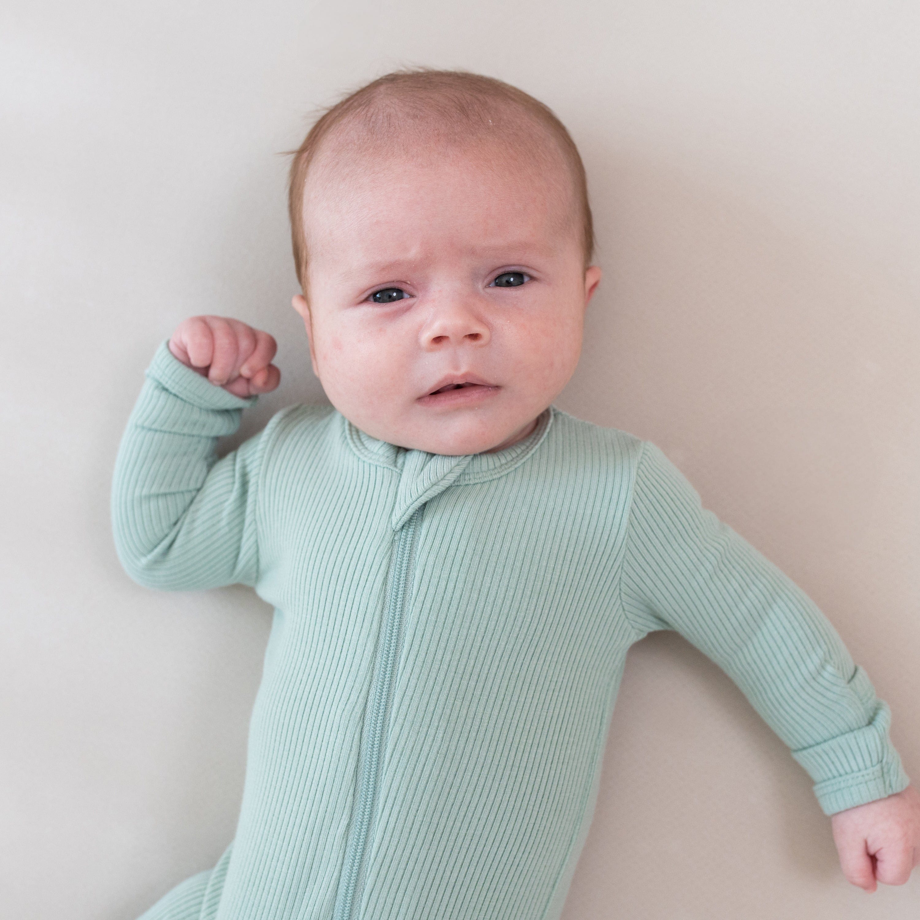 Baby wearing Kyte Baby bamboo Ribbed Zippered Footie in Sage