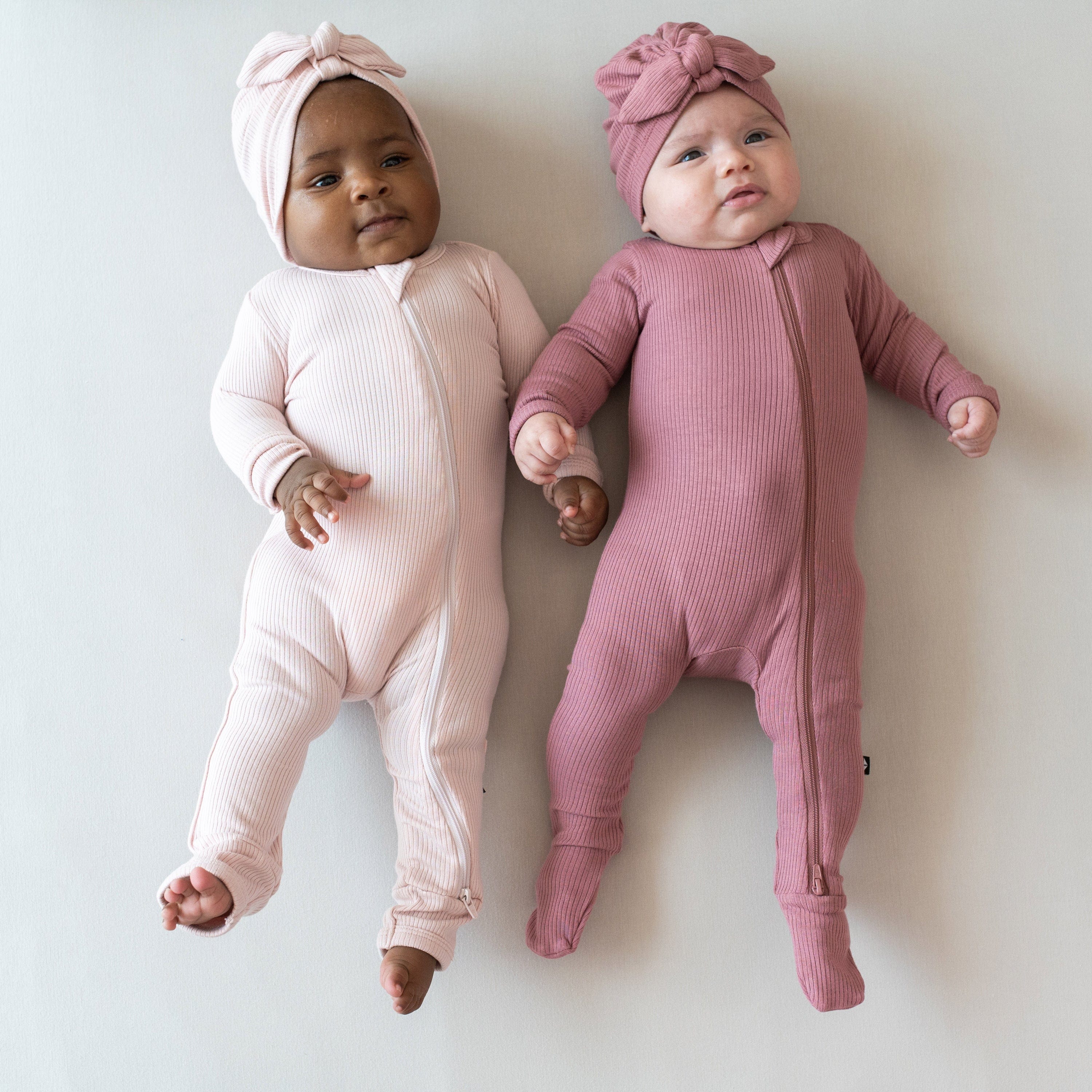Infants wearing Kyte Baby Ribbed Zippered Rompers