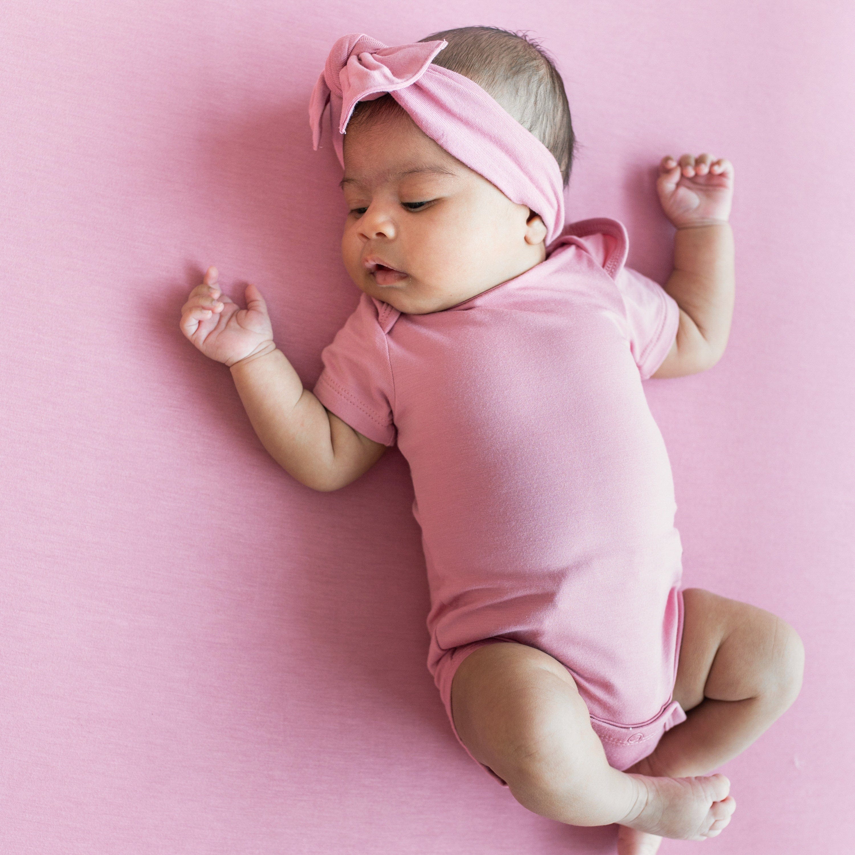 Infant wearing Short Sleeve Bodysuit in Apple Blossom with matching pink bow headband