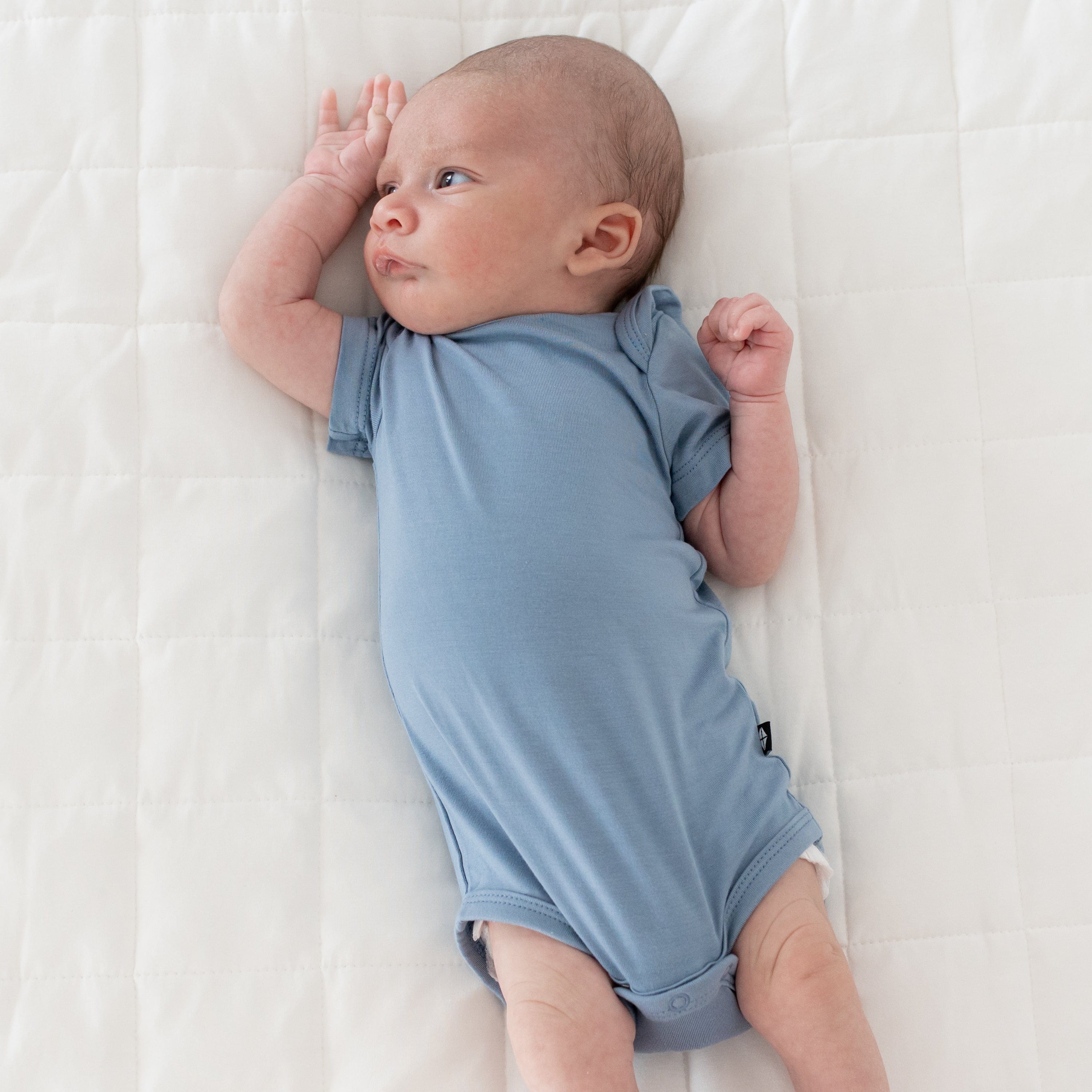 Newborn wearing Kyte Baby Bodysuit in Slate