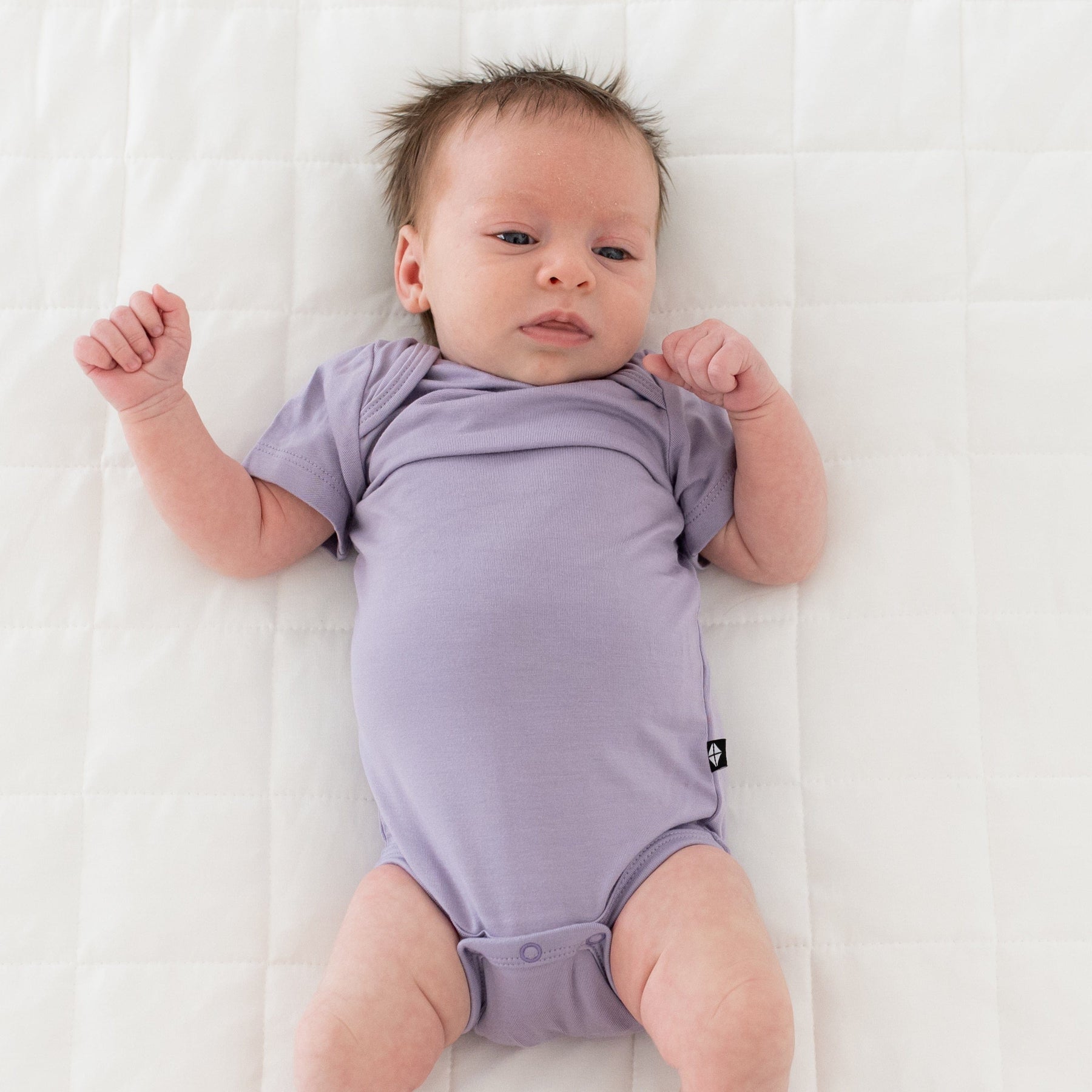 Baby wearing Kyte Baby infant Bodysuit in Taro