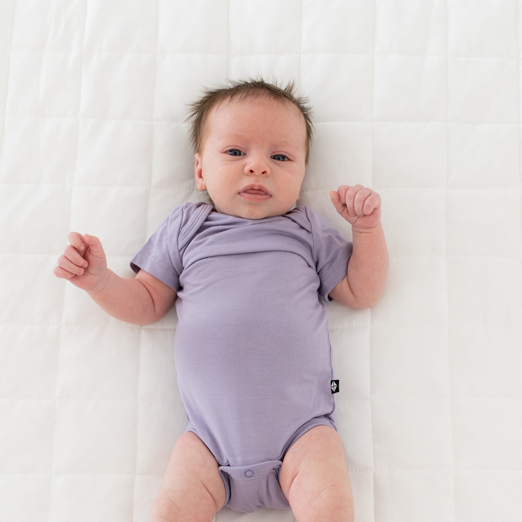 Newborn wearing Kyte Baby Bodysuit in Taro