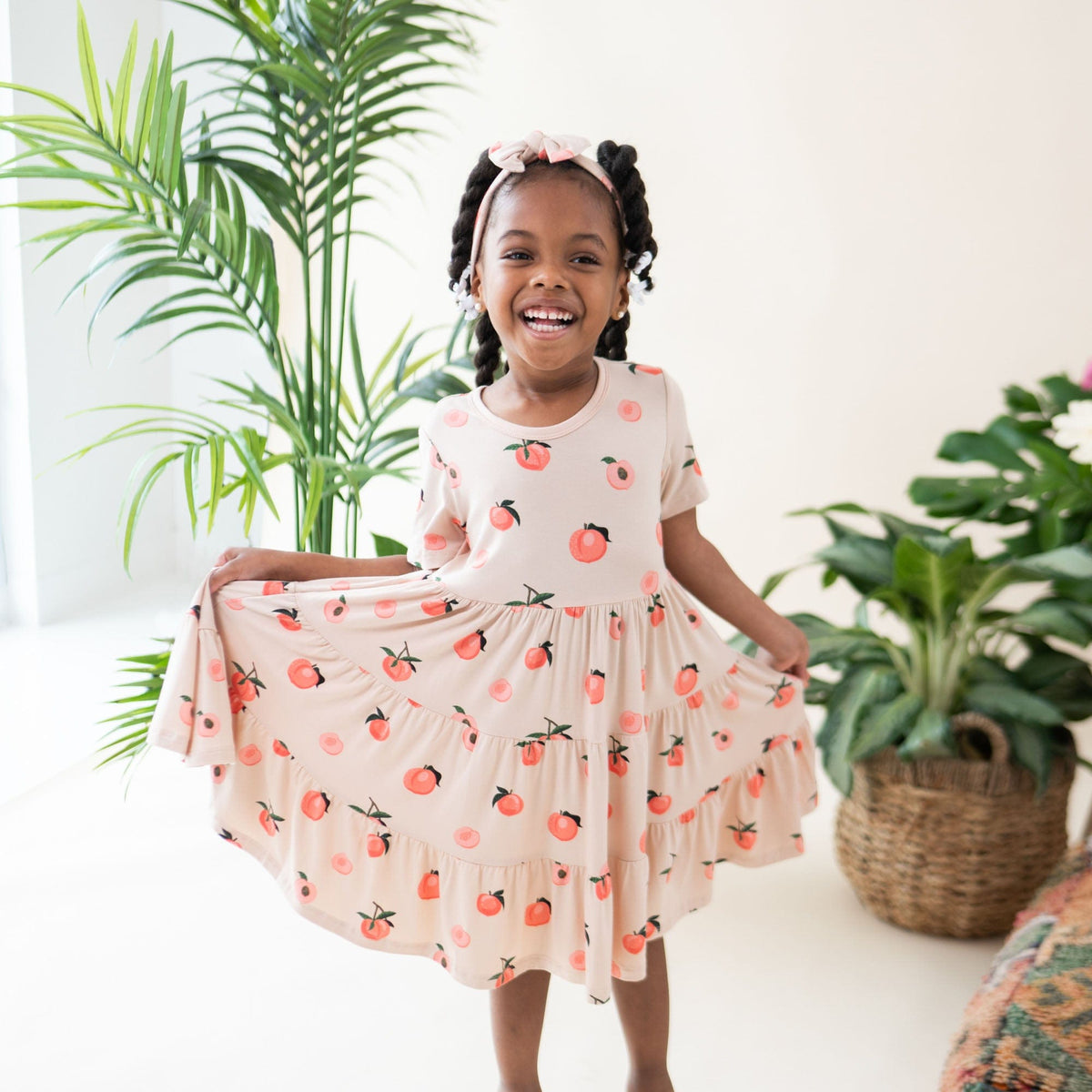 Toddler twirling in Kyte Baby Short Sleeve Tiered Dress in Peach