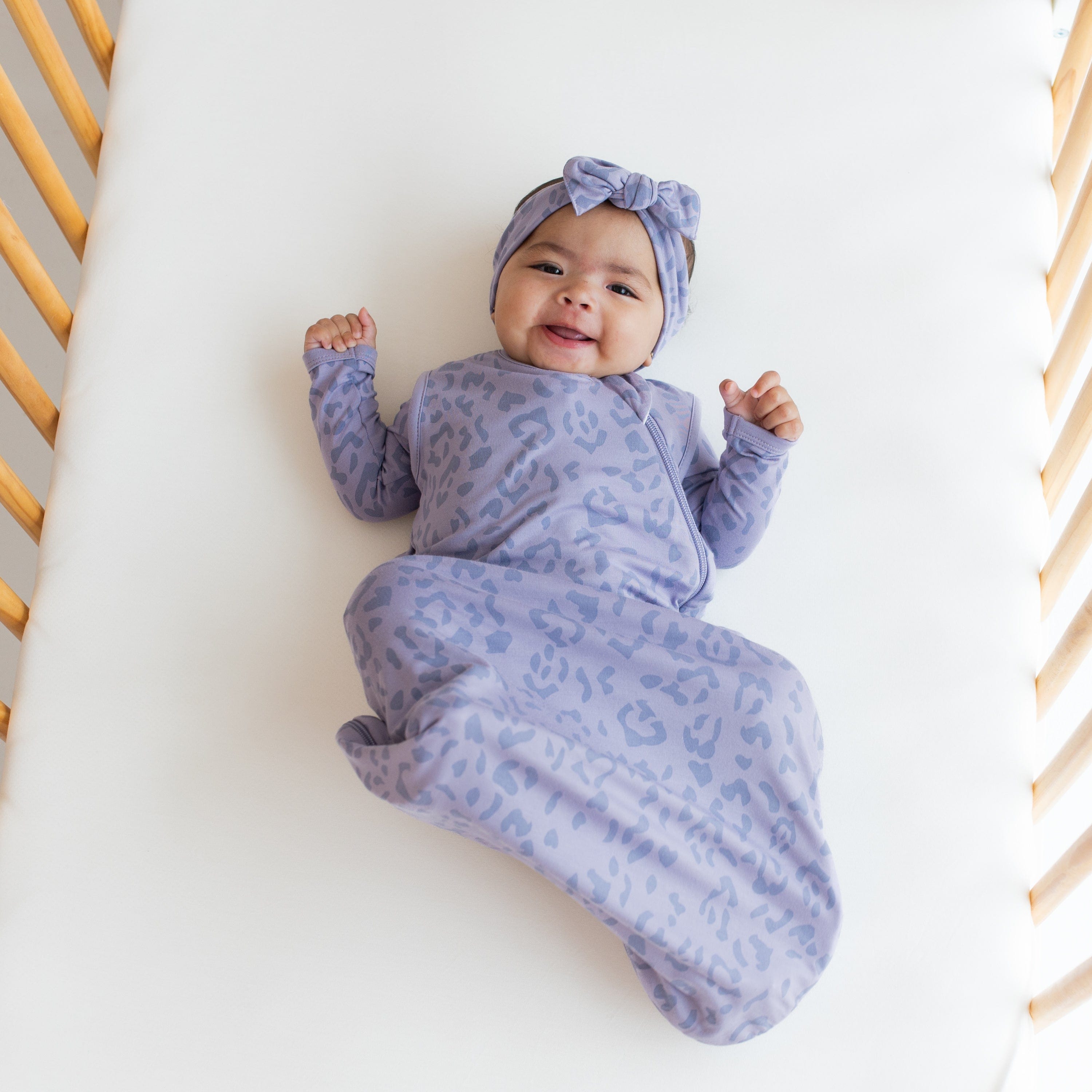 Infant wearing Kyte Baby Sleep Bag in Taro Leopard 0.5