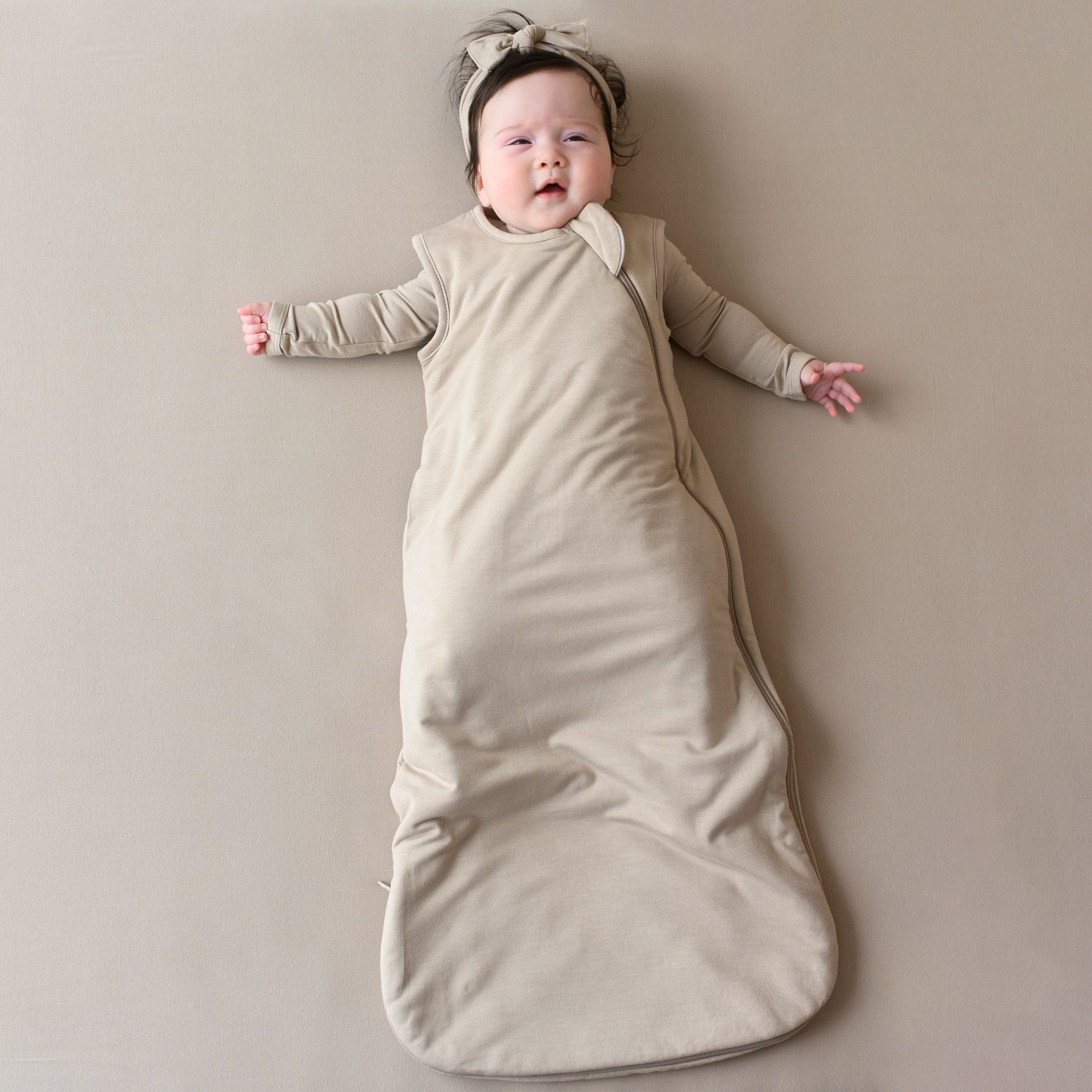 Baby modeling Kyte Baby Sleep Bag in Almond 1.0