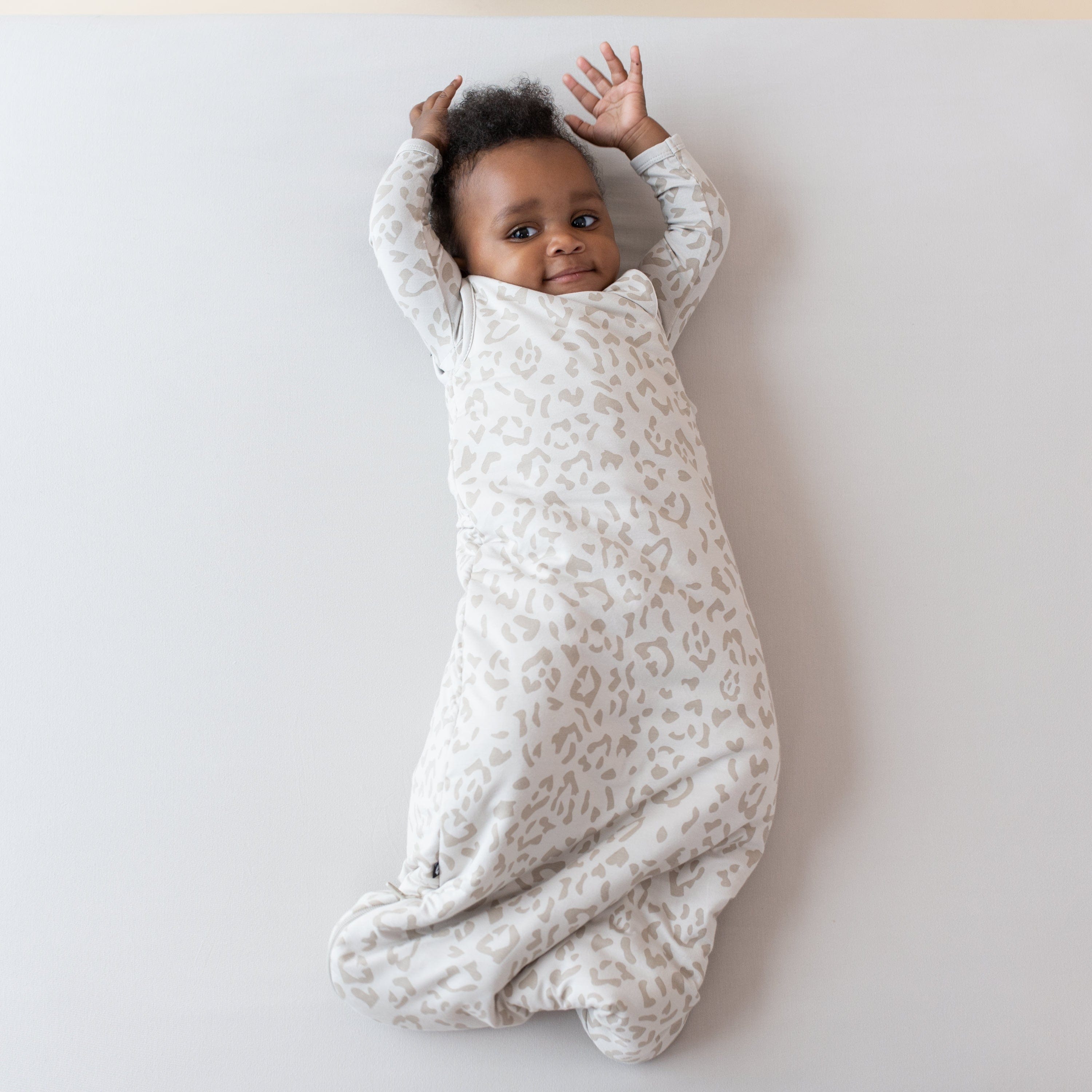 Infant wearing Kyte Baby Sleep Bag in Oat Leopard 1.0