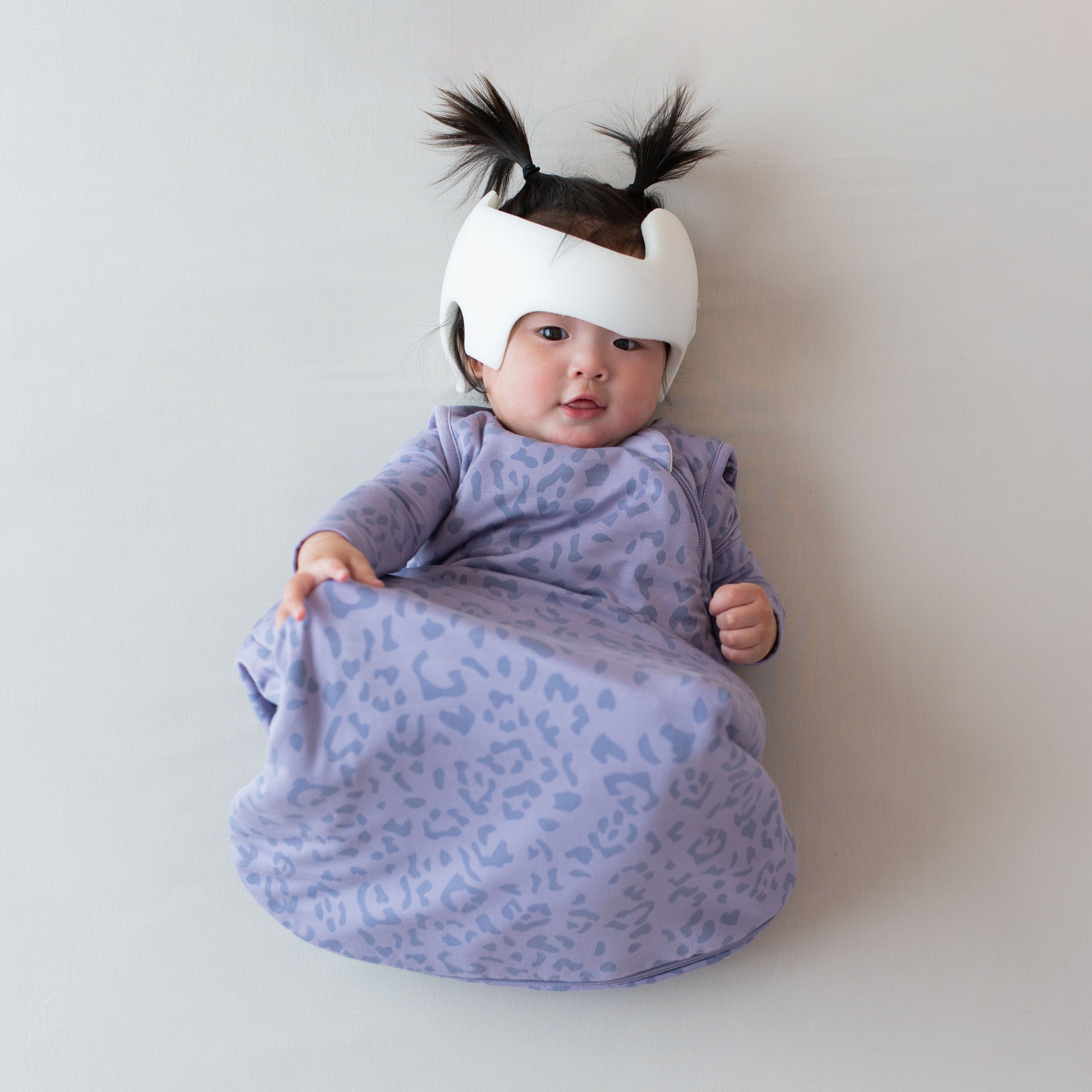 Infant wearing Kyte Baby Sleep Bag in Taro Leopard 1.0