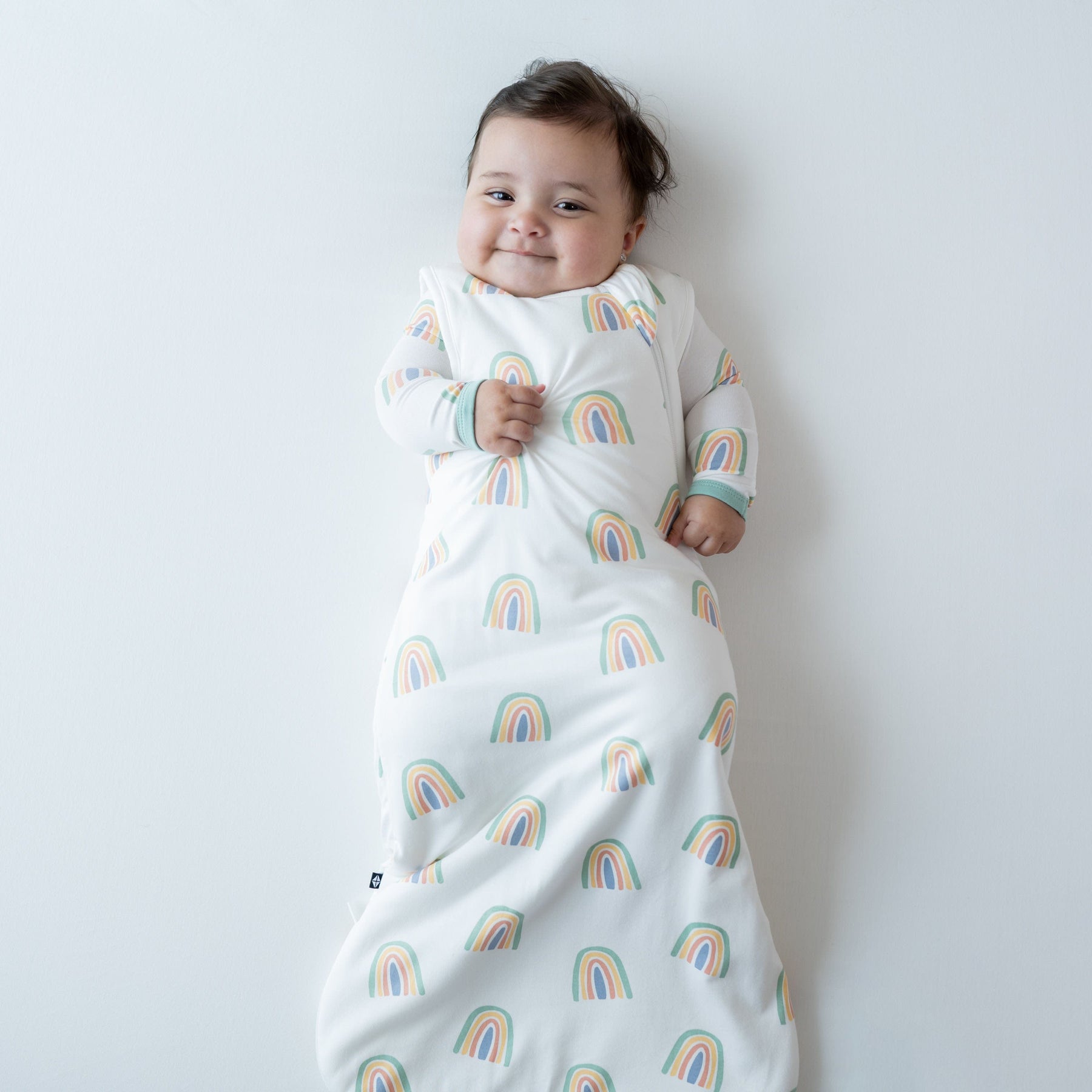 Infant wearing Kyte Baby Sleep Bag TOG 1.0 in Wasabi Rainbow pattern