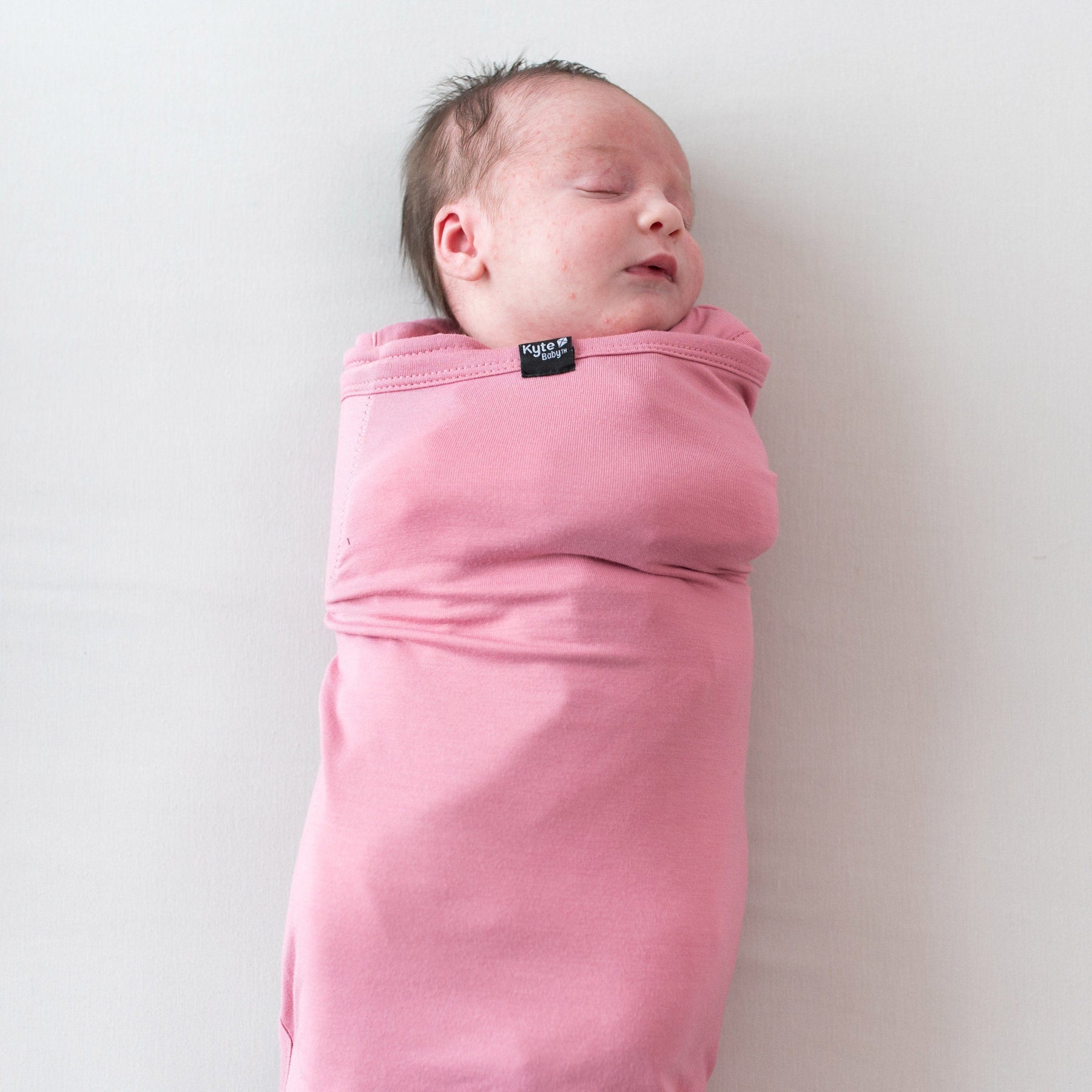 Newborn sleeping in Kyte Baby Sleep Bag Swaddler in Apple Blossom