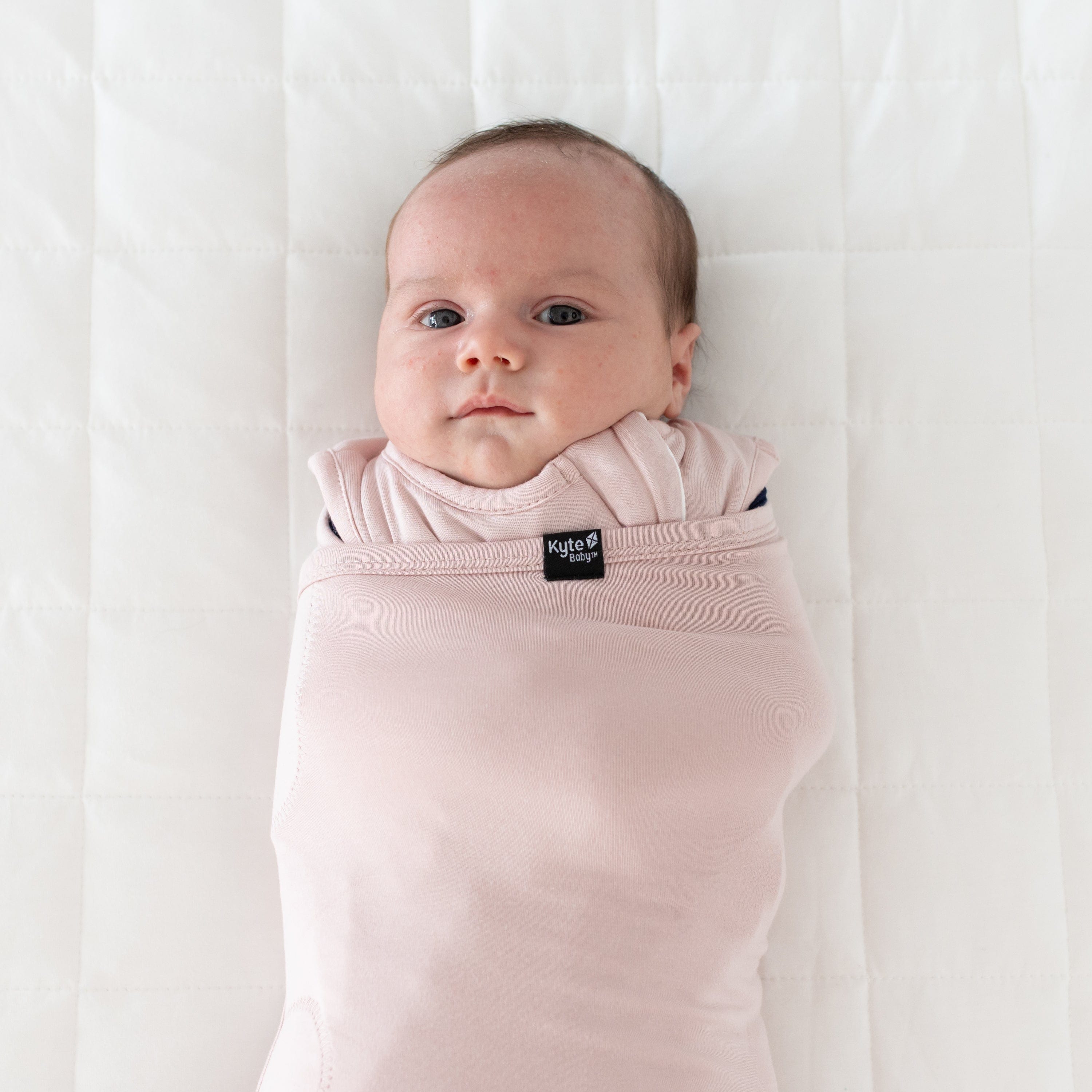 Baby wearing Kyte Baby Sleep Bag with Swaddle Band in Blush