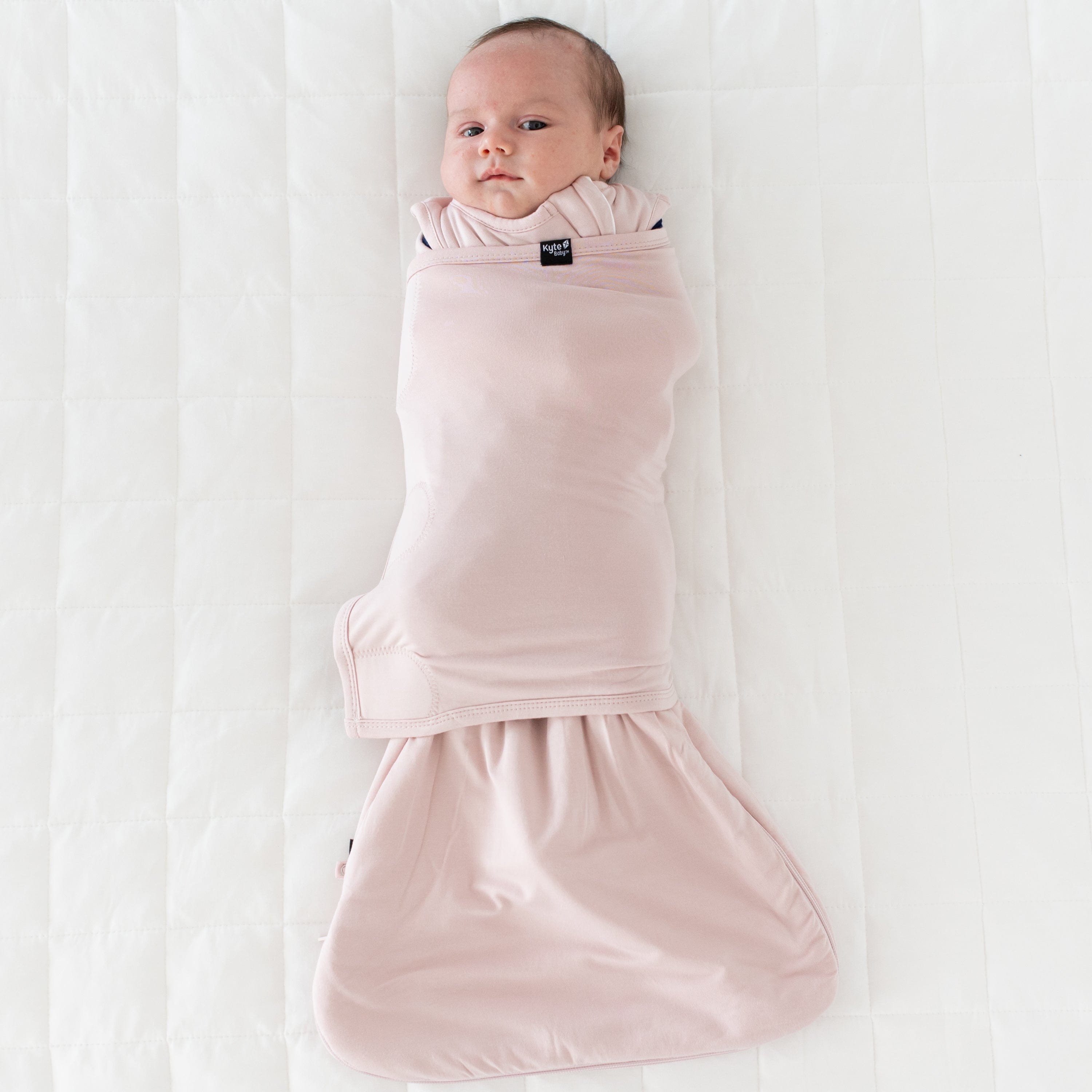 Baby wearing Kyte Baby Sleep Bag Swaddler in Blush