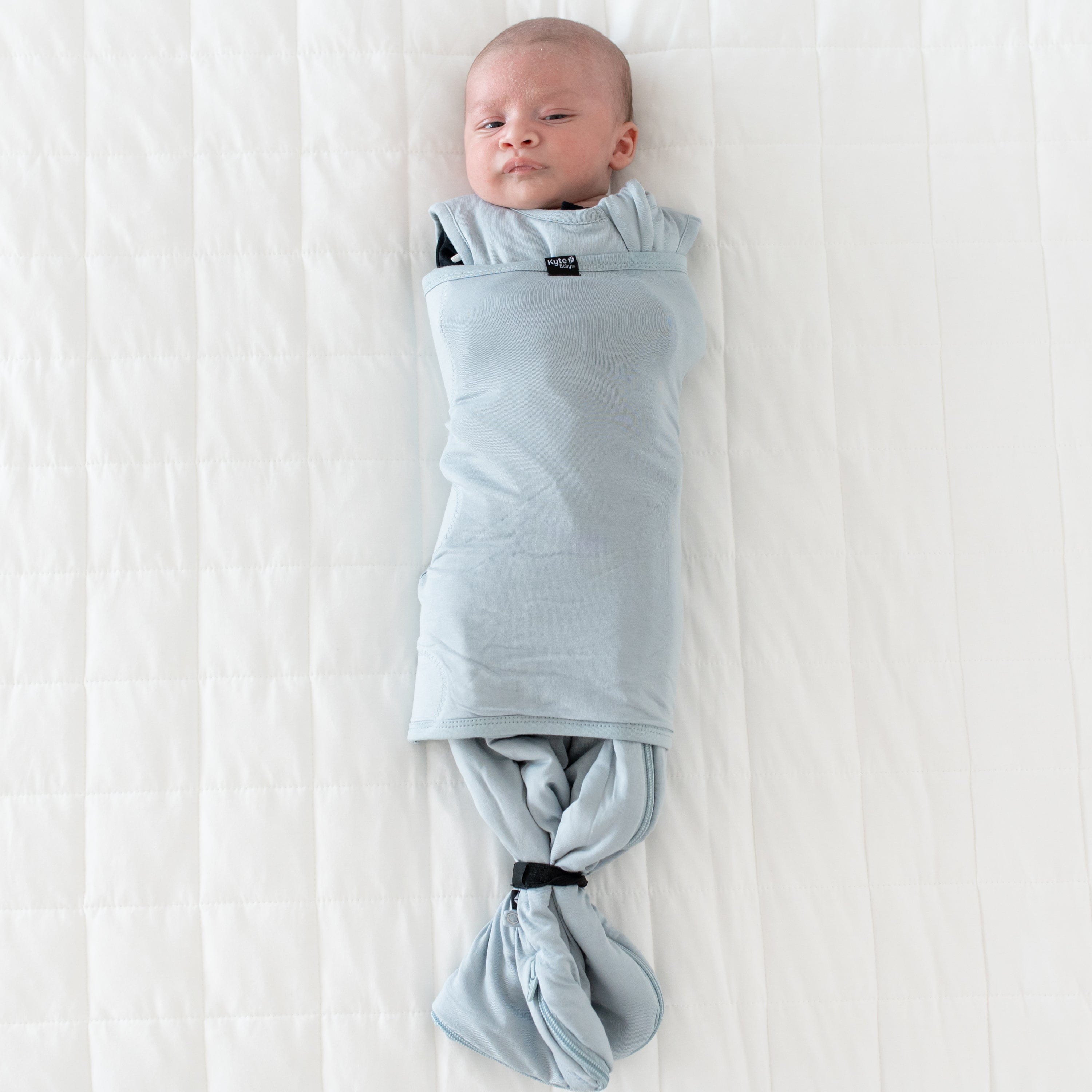 Baby wearing Kyte Baby Sleep Bag Swaddler in Fog with elastic band