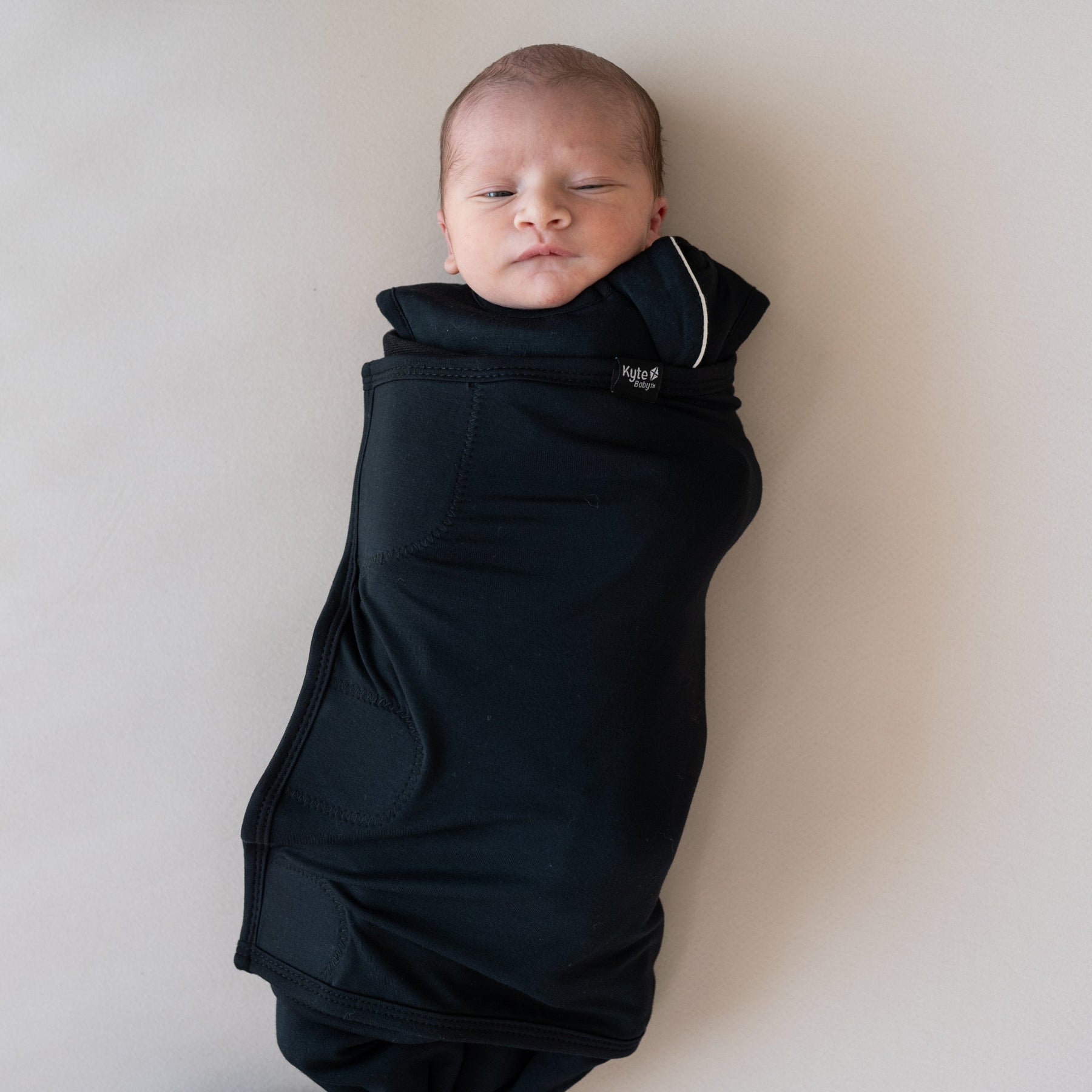 Baby wearing Kyte Baby bamboo Sleep Bag Swaddler in Midnight