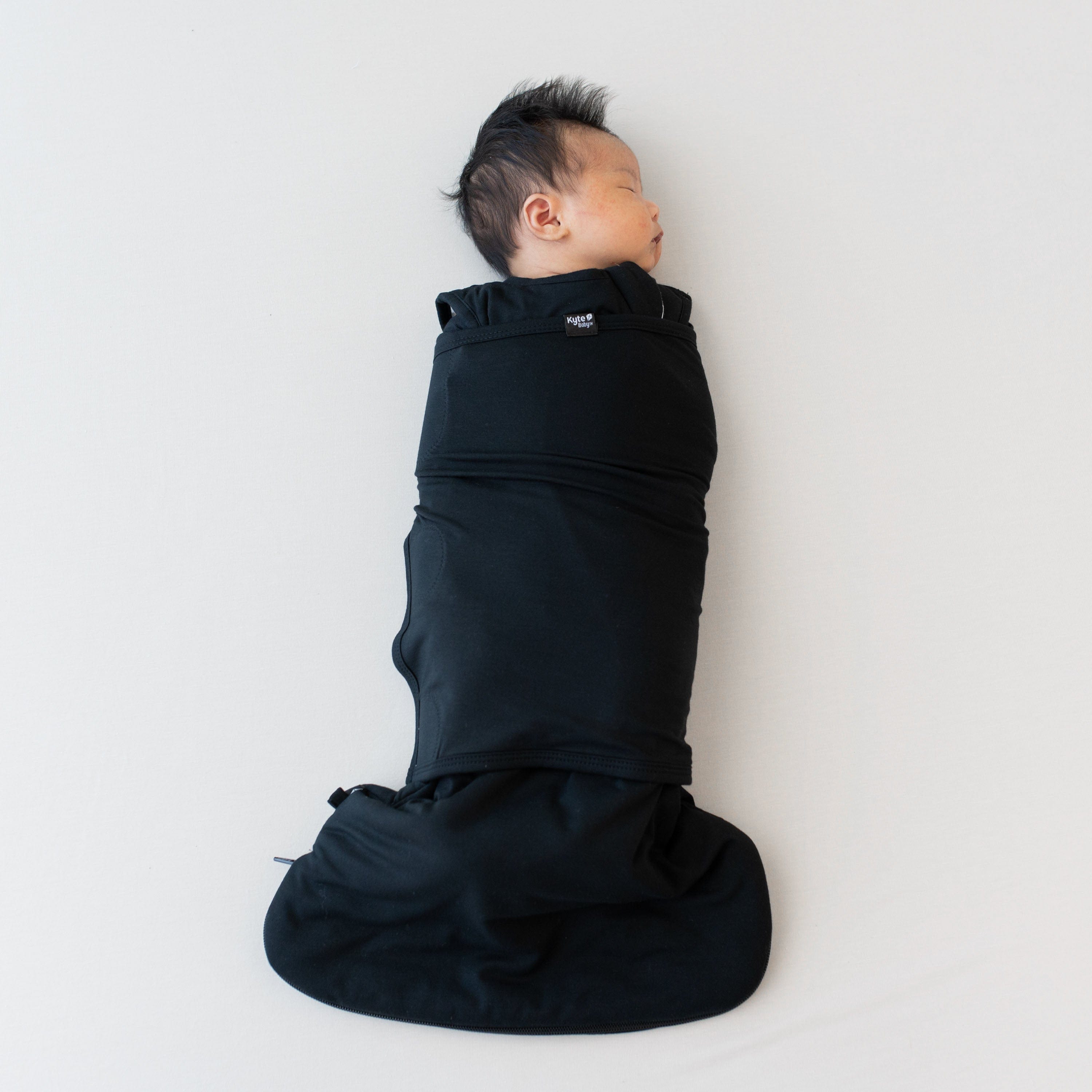 Sleeping baby swaddled in the Sleep Bag Swaddler in Midnight 1.0