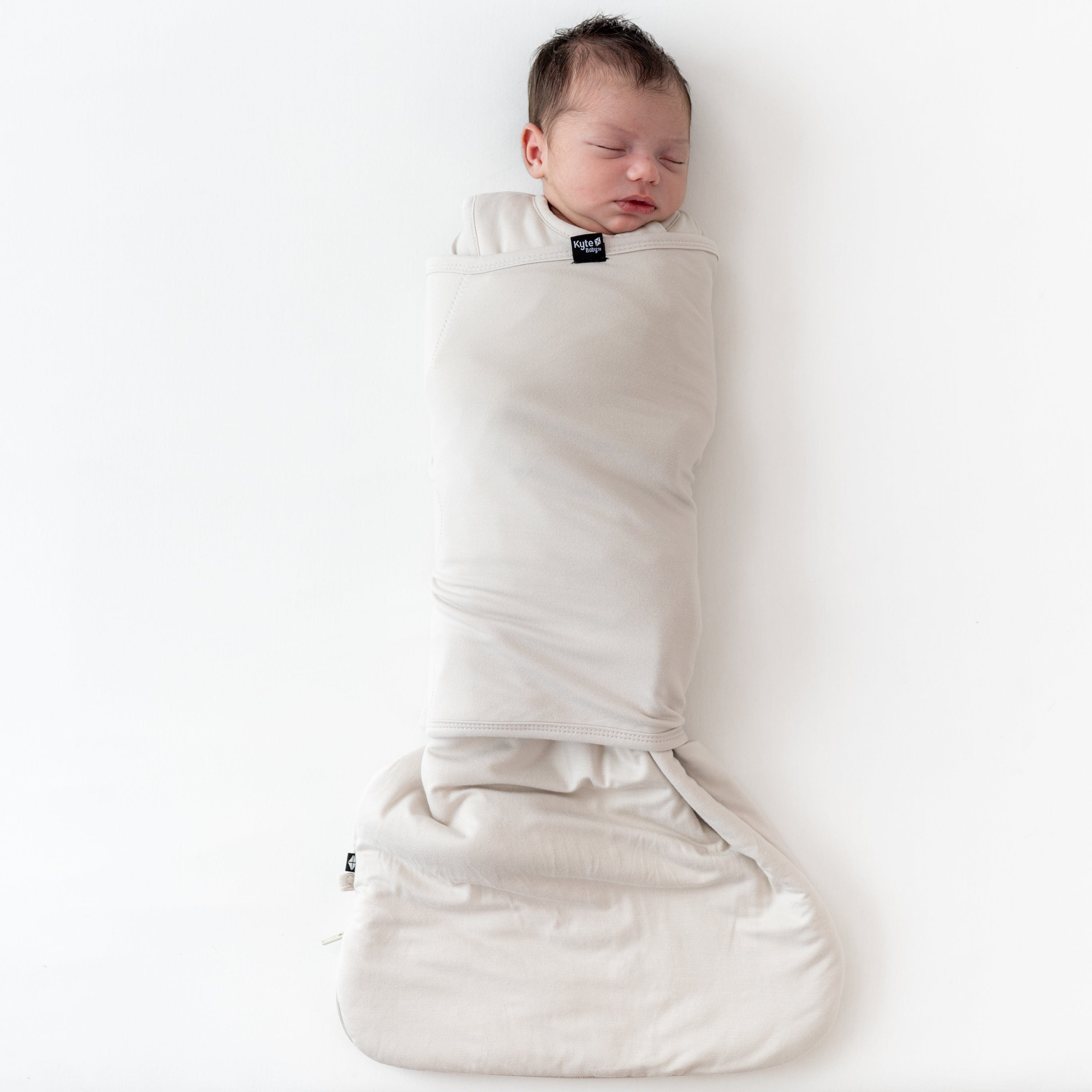 Baby sleeping in Kyte Baby Sleep Bag Swaddler in Oat