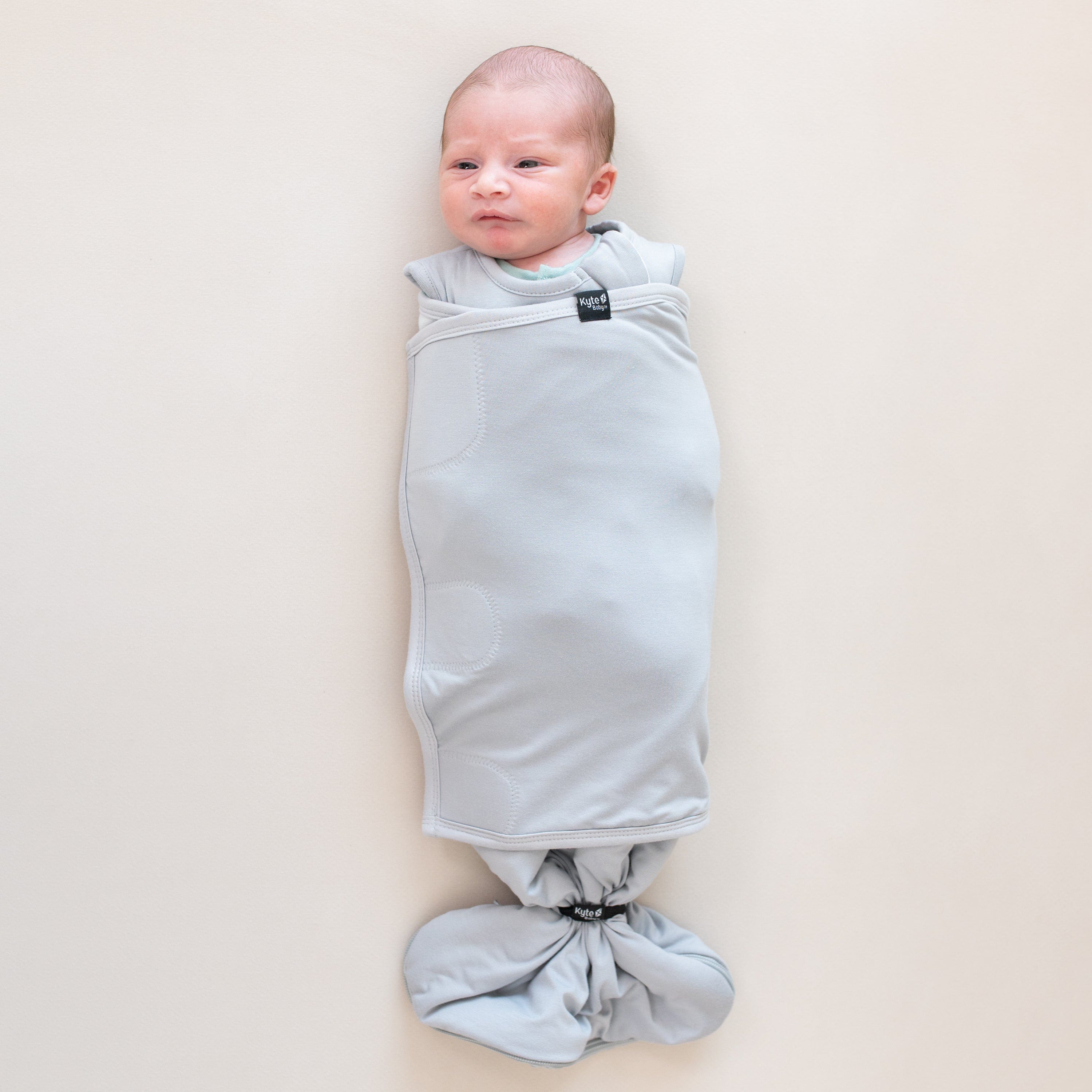 Baby wearing Kyte Baby Sleep Bag Swaddler in Storm with elastic band