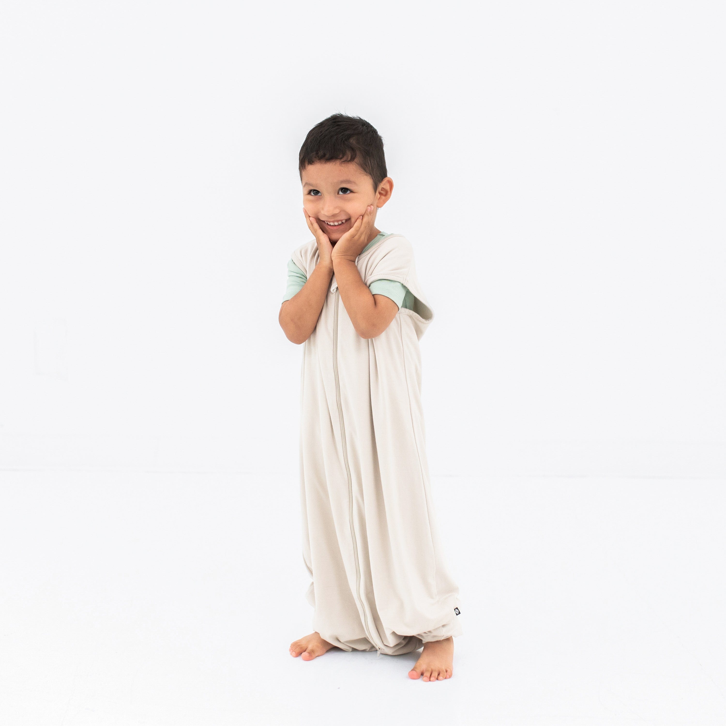 Model wearing the Sleep Bag Walker in Oat 0.5 with hands on his face