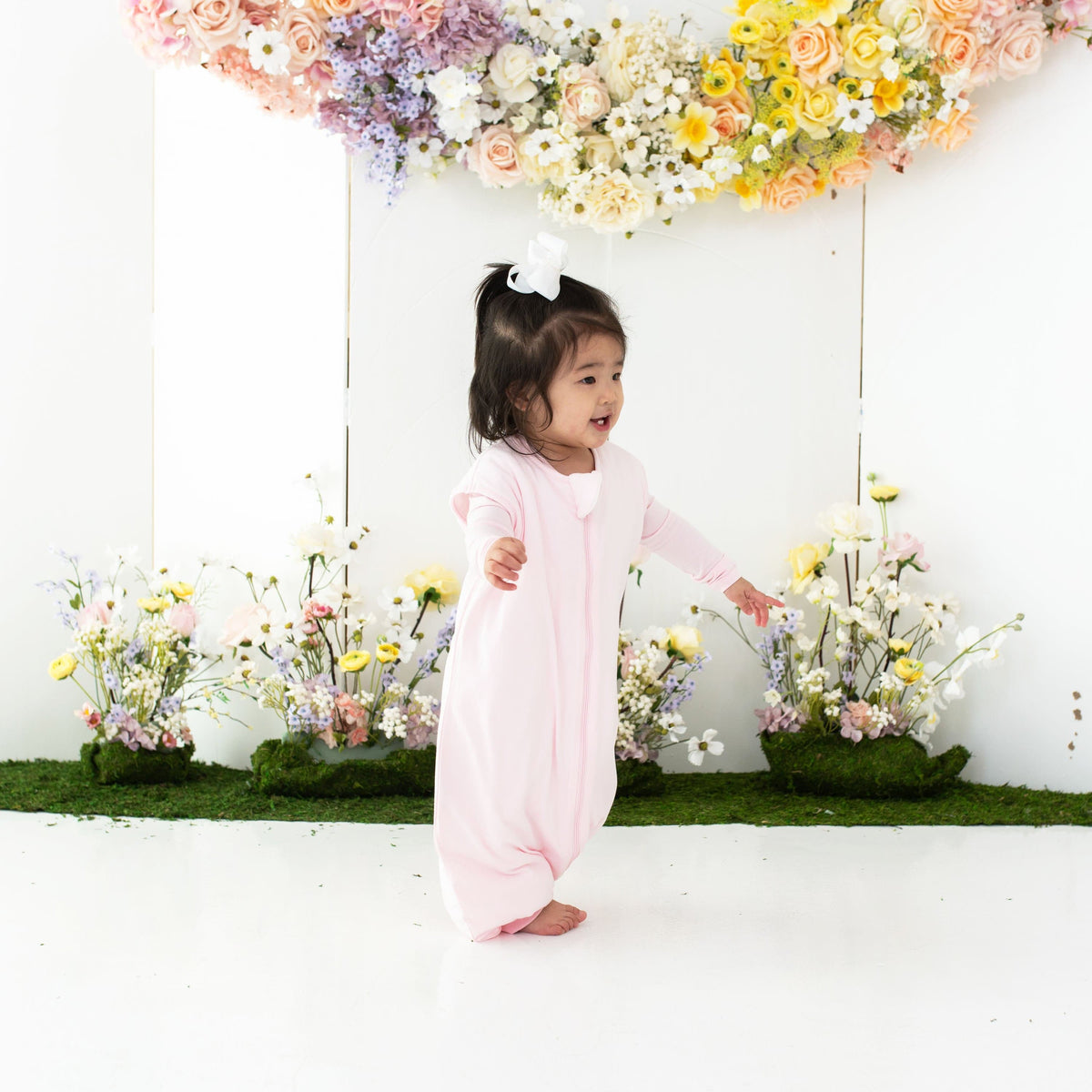 Toddler walking wearing Kyte Baby TOG 1.0 Sleep Bag Walker in Sakura pink