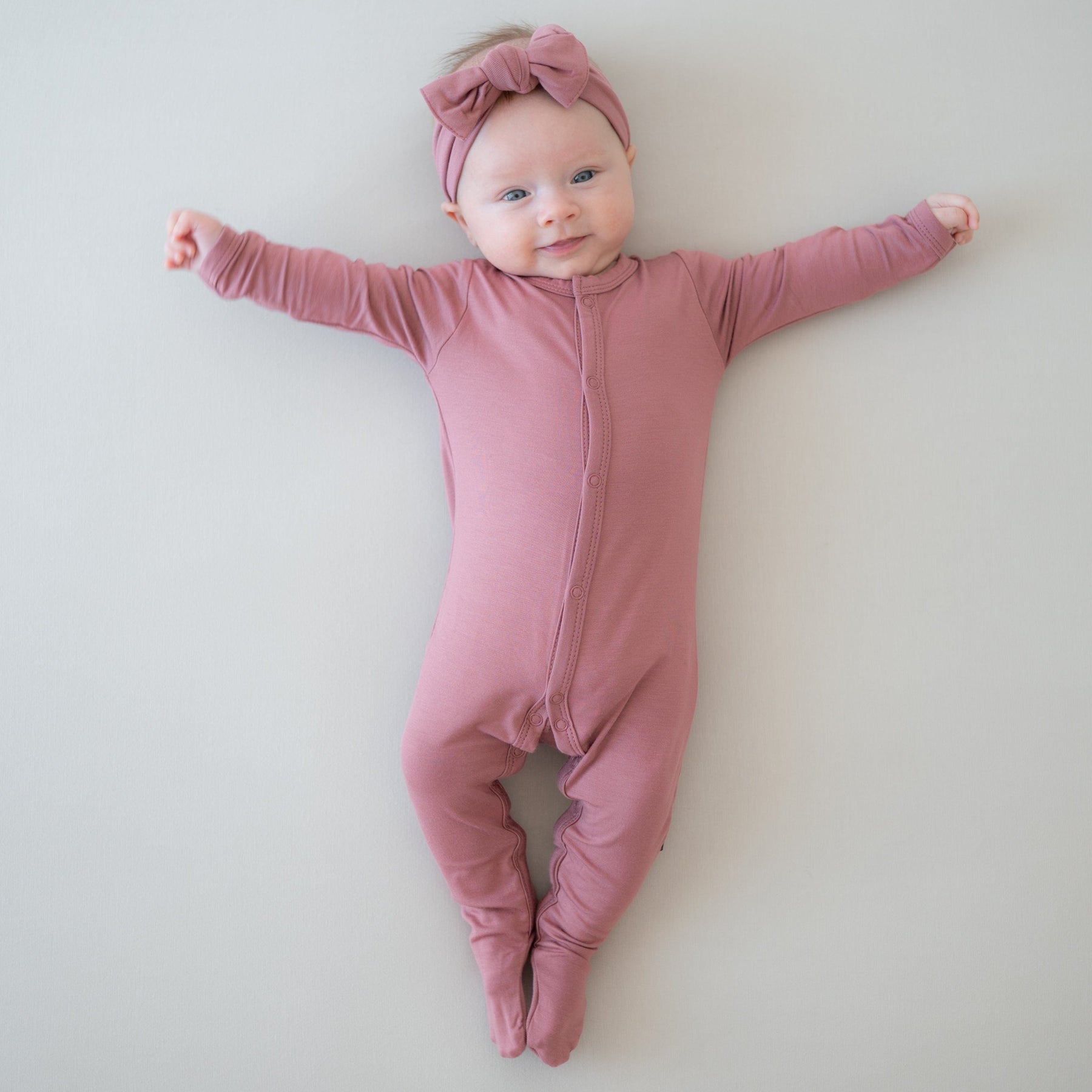 Infant wearing Kyte Baby Snap Footie pajamas in Dusty Rose
