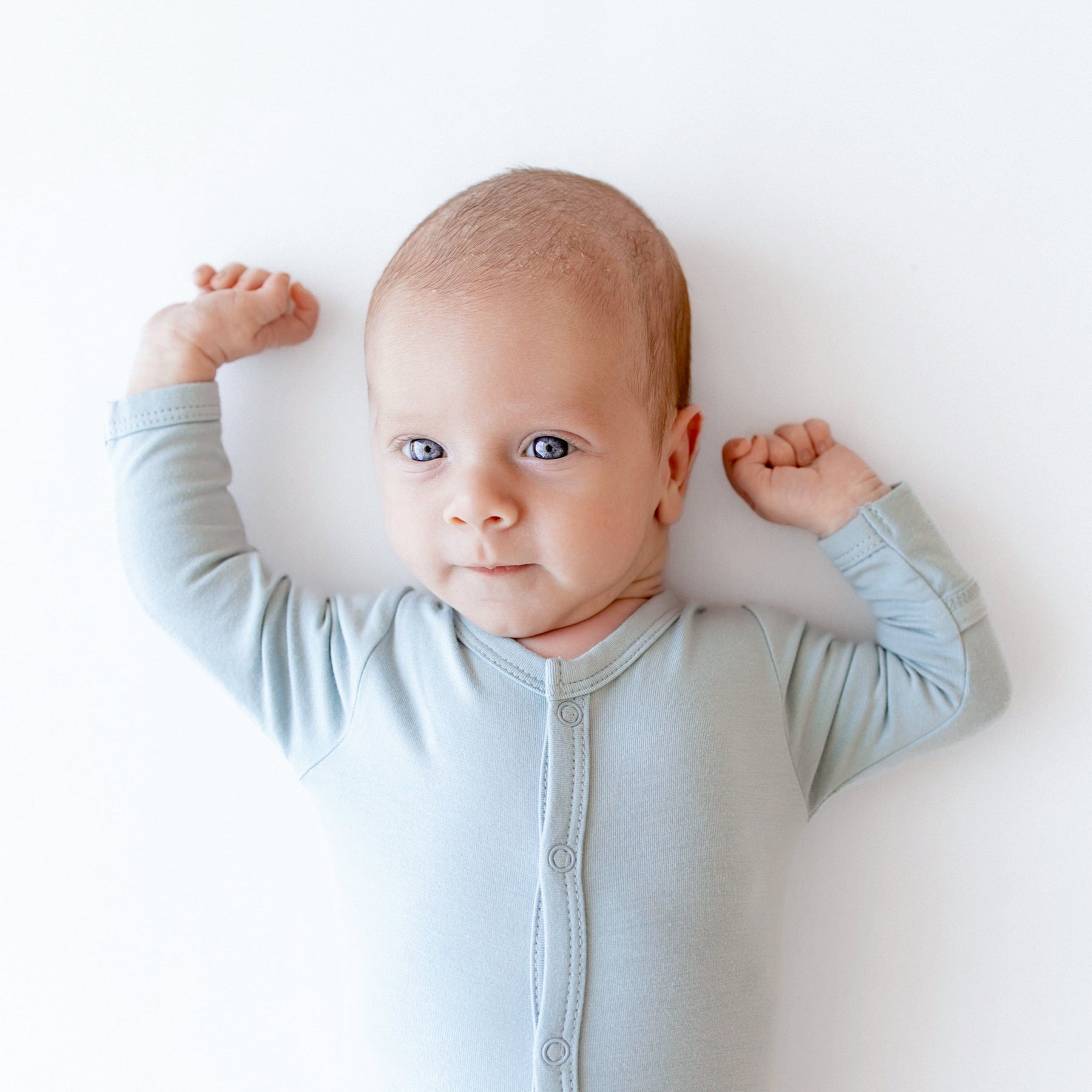 Infant wearing Kyte Baby Snap Footie pajamas in Fog